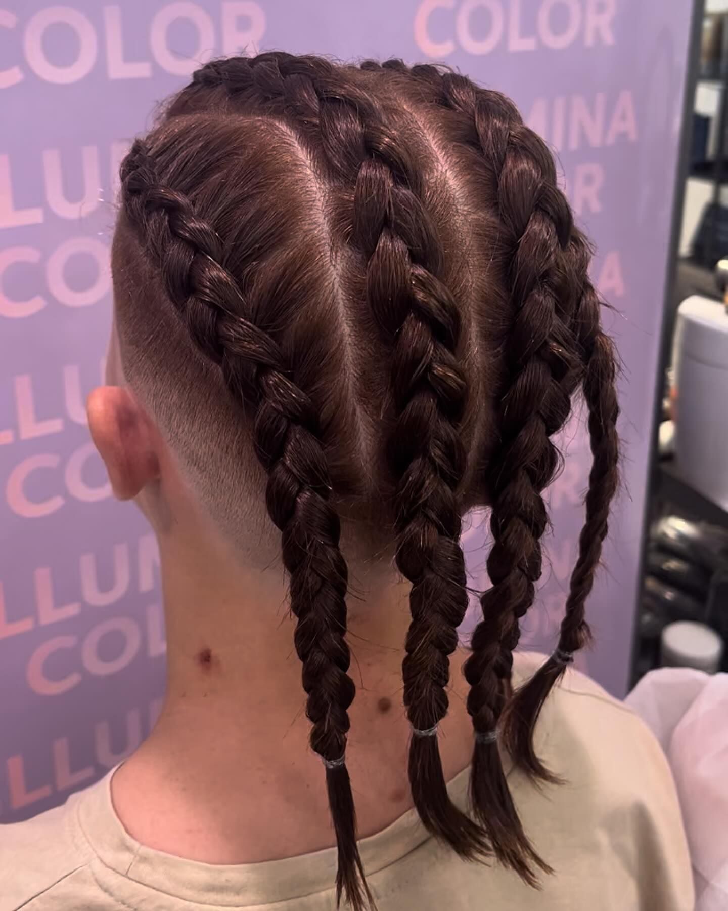 Una donna con le trecce nei capelli è in piedi davanti a un cartello che dice colore