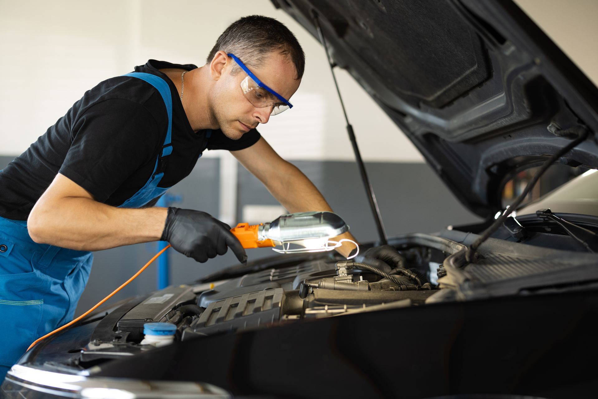 A man is working on the engine of a car in a garage.