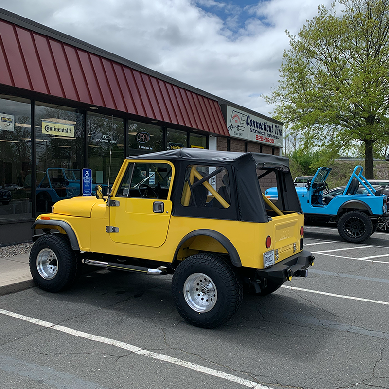 A yellow jeep is parked in front of a building