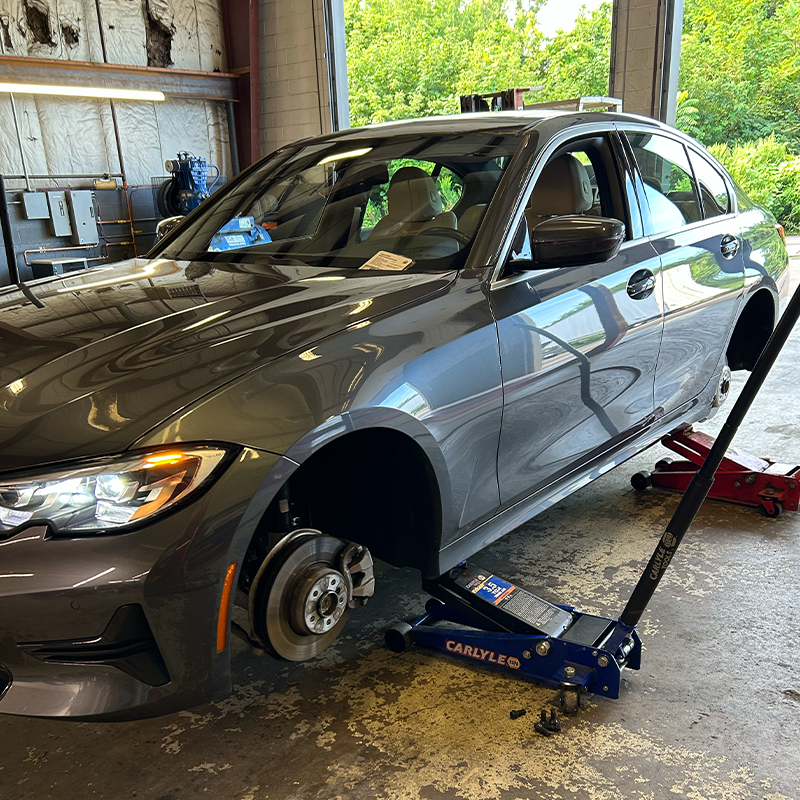 A car is sitting on a jack in a garage.