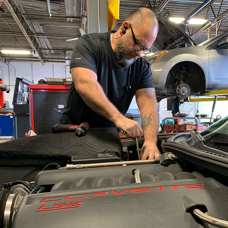 A man is working on the engine of a car in a garage.