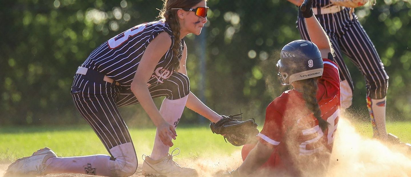 A girl is sliding into a base during a softball game.