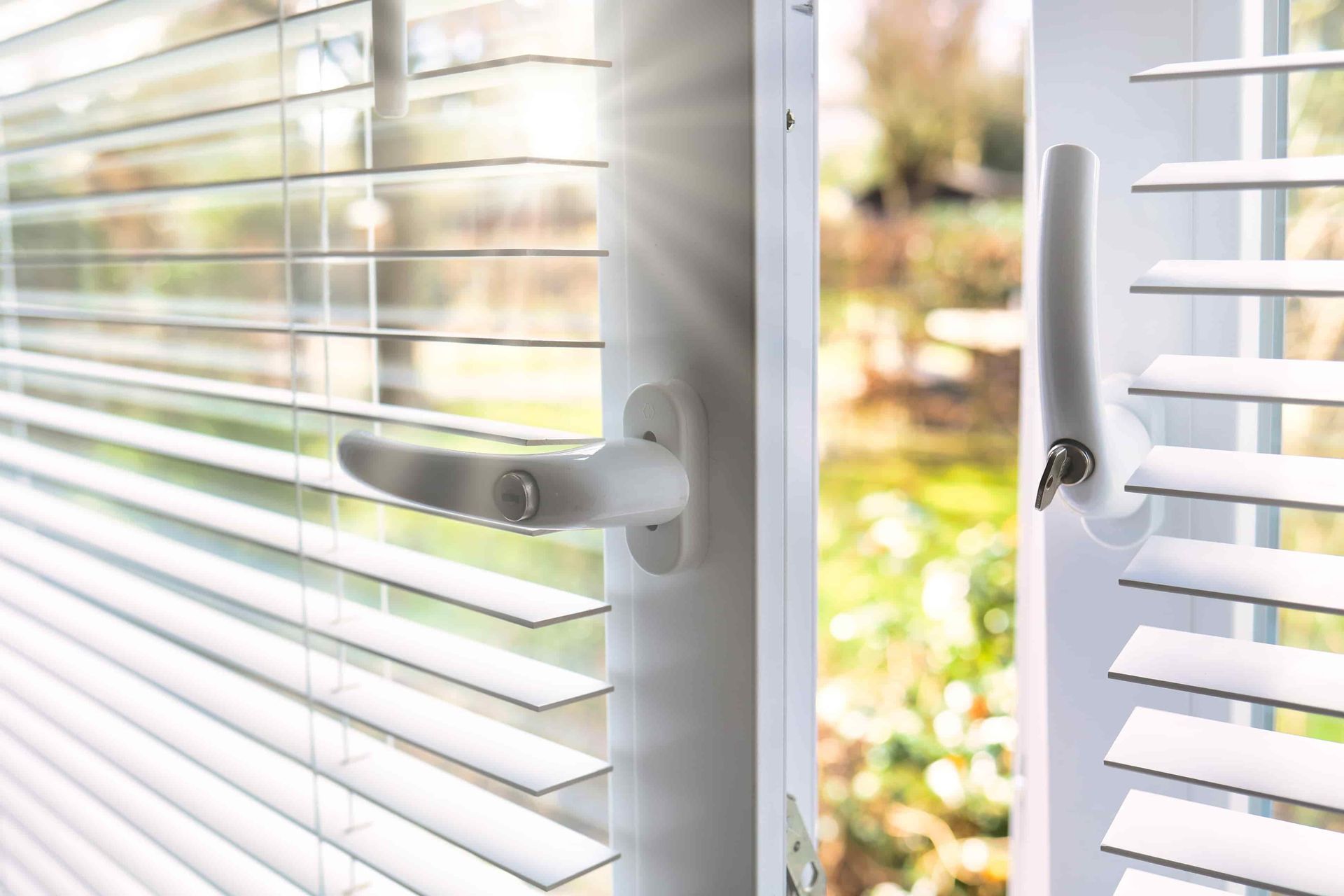 Hand opening a window, sunlight streaming in; a plant on the windowsill.