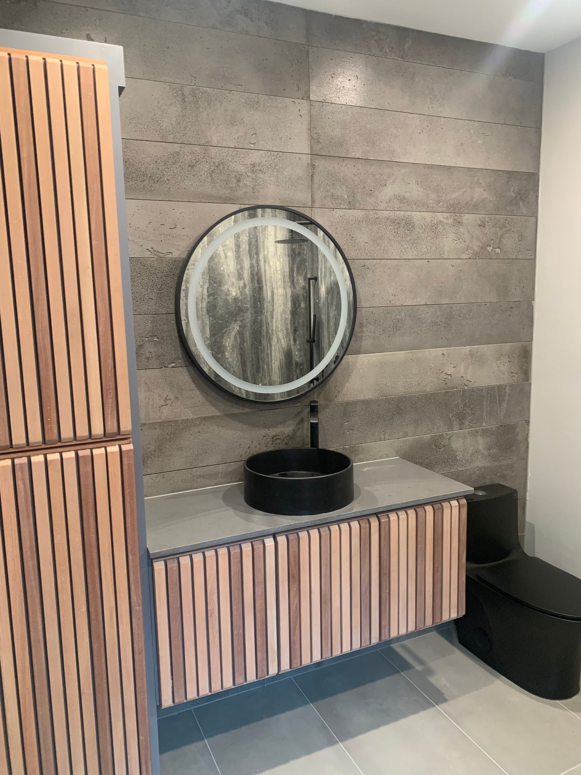 Modern shower with dark gray stone-look wall panels, black shower fixtures, and light tile floor.