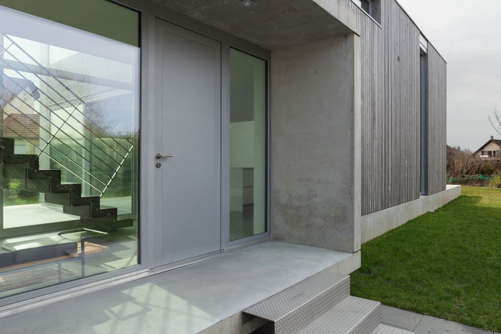 A modern house with a large glass door and stairs.