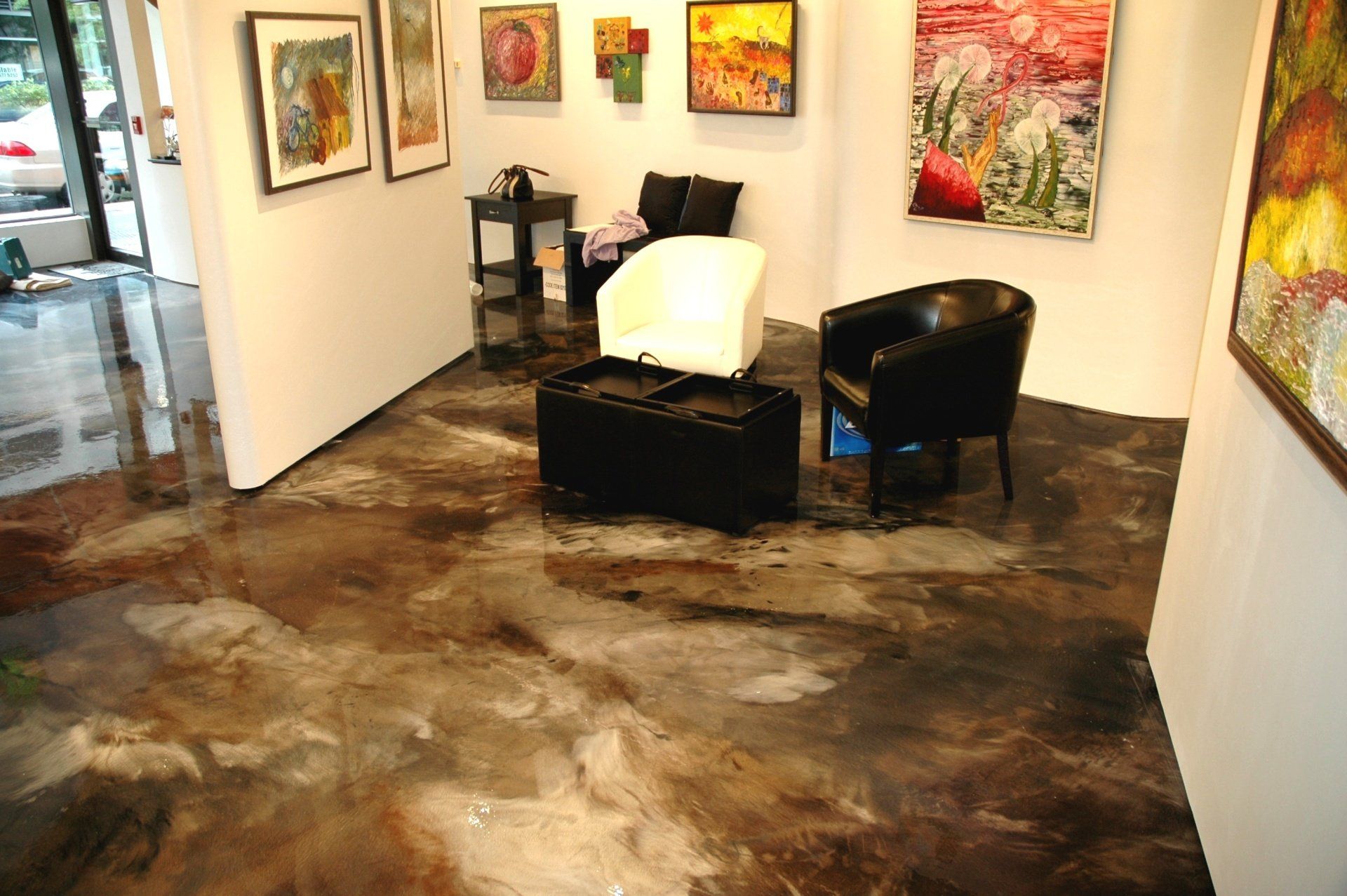 A living room with paintings on the walls and a concrete floor