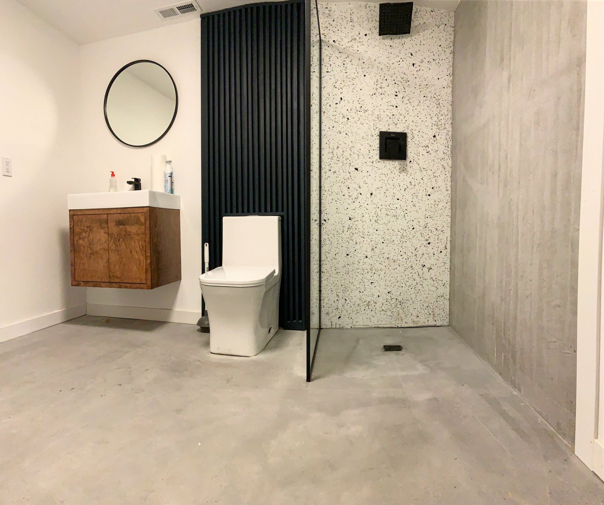 A bathroom with a toilet , sink , mirror and walk in shower.