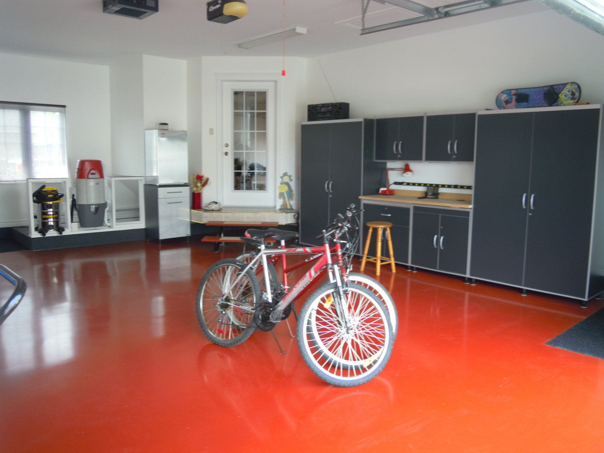Two bikes are parked in a garage with red floors