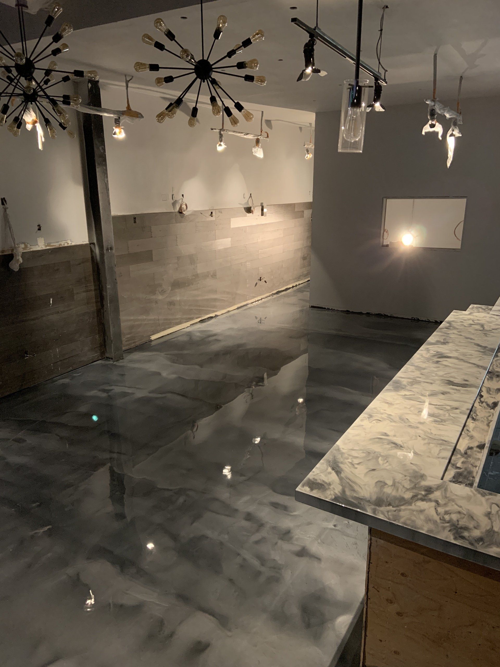 A kitchen with a marble counter top and a metallic floor.