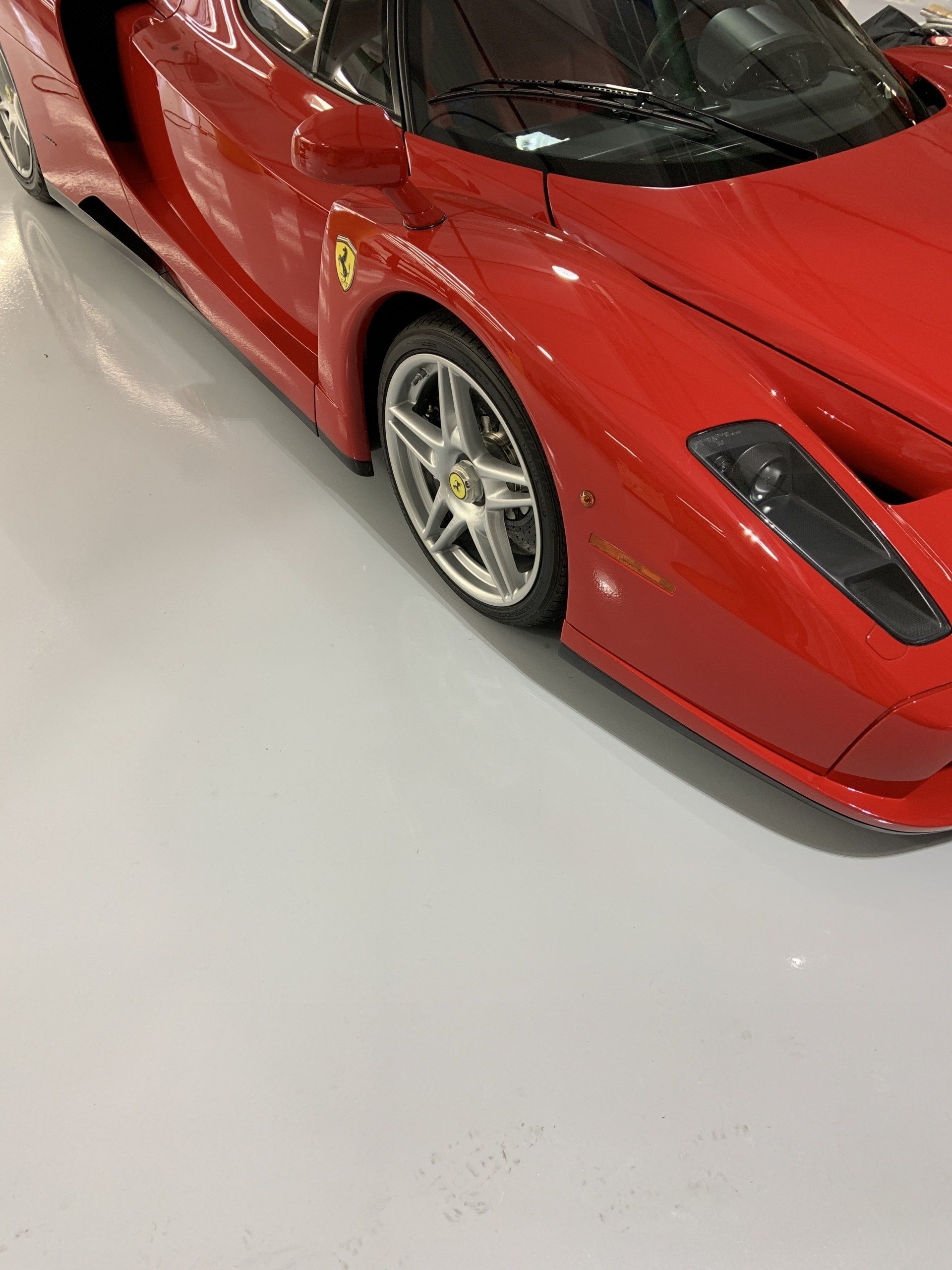 A red sports car is parked on a white floor