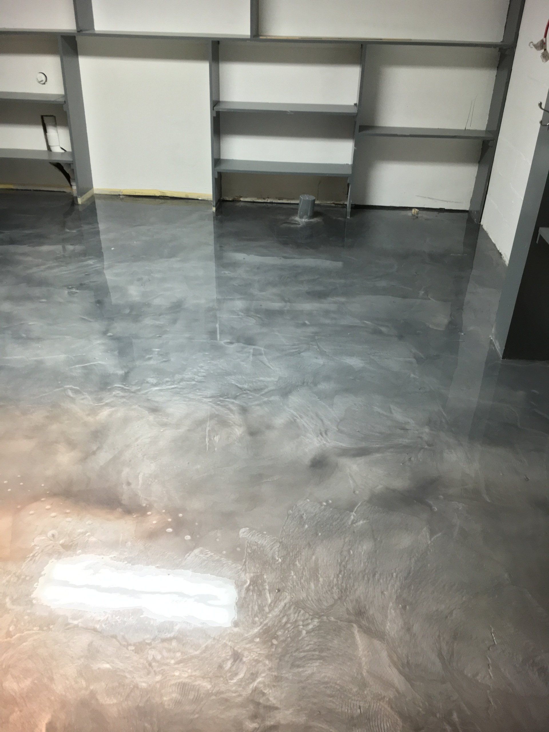 A shiny metallic floor in a room with shelves.