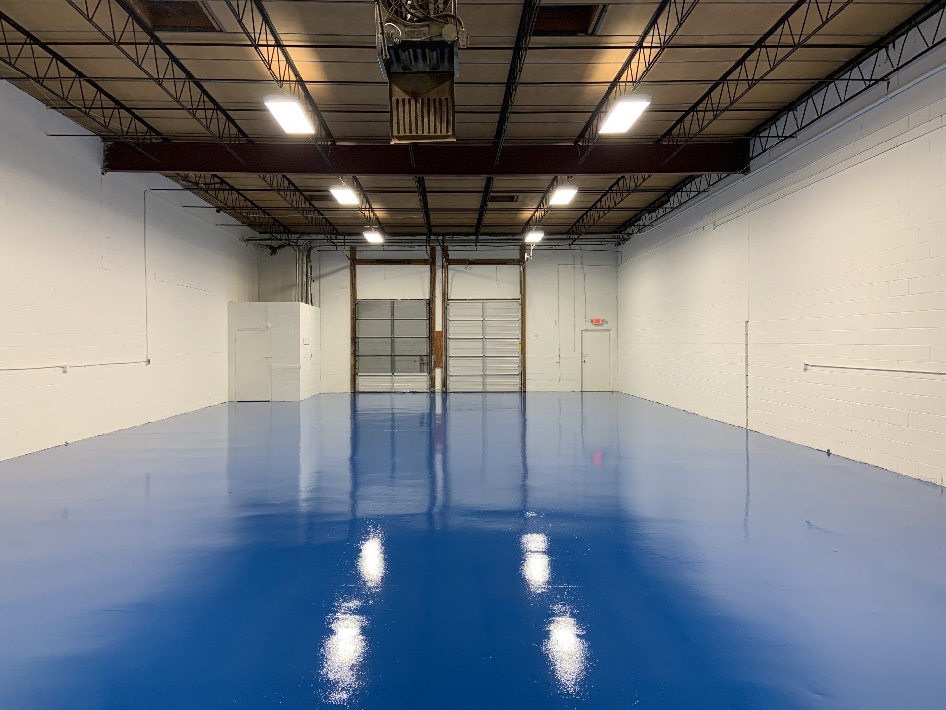 A large empty warehouse with a blue floor and white walls.