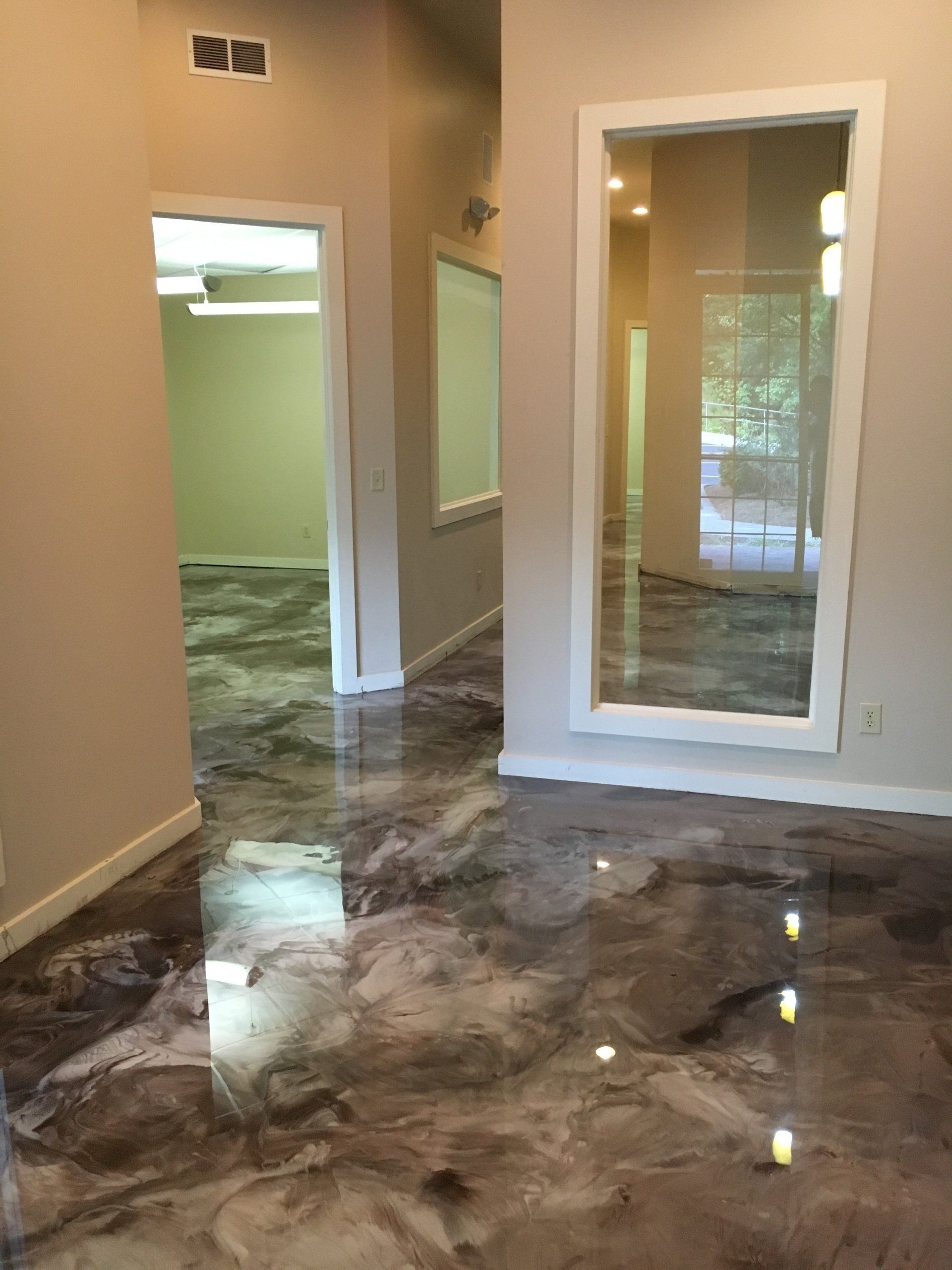 A hallway with a large mirror on the wall and a metallic floor.