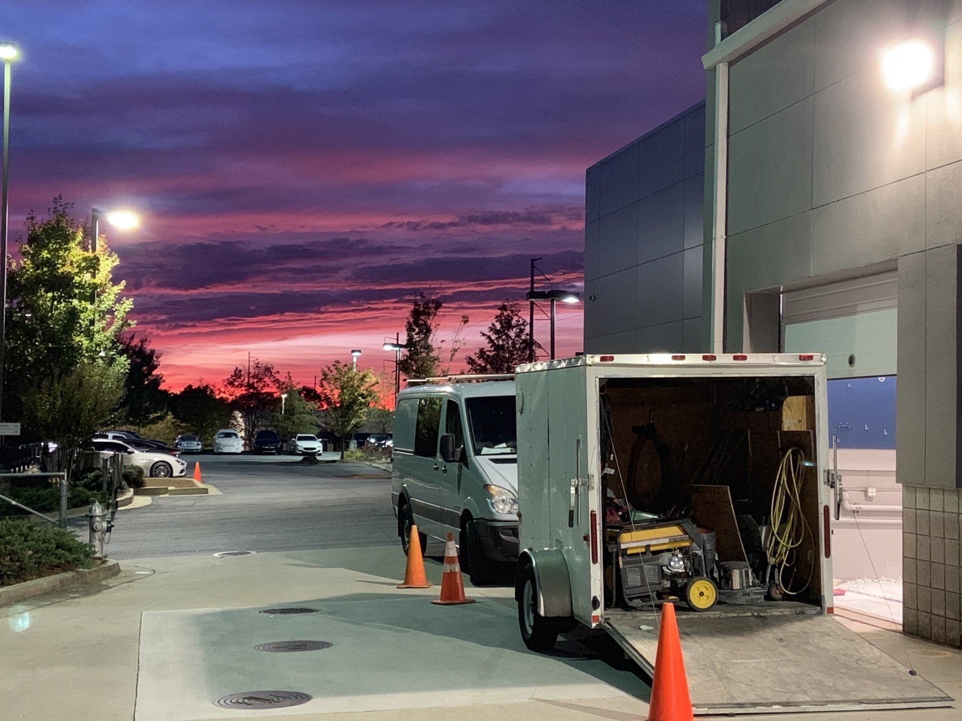 A white van is parked in a parking lot with a sunset in the background