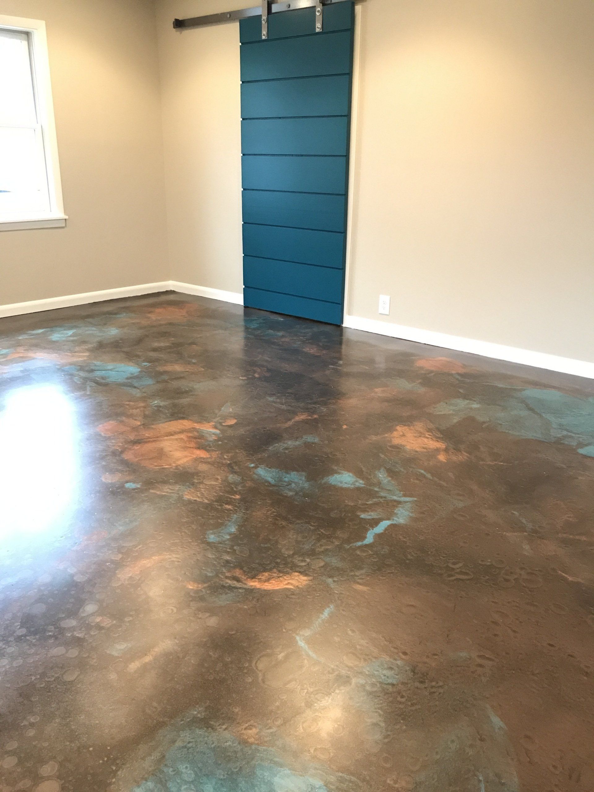 A room with a sliding barn door and a concrete floor.
