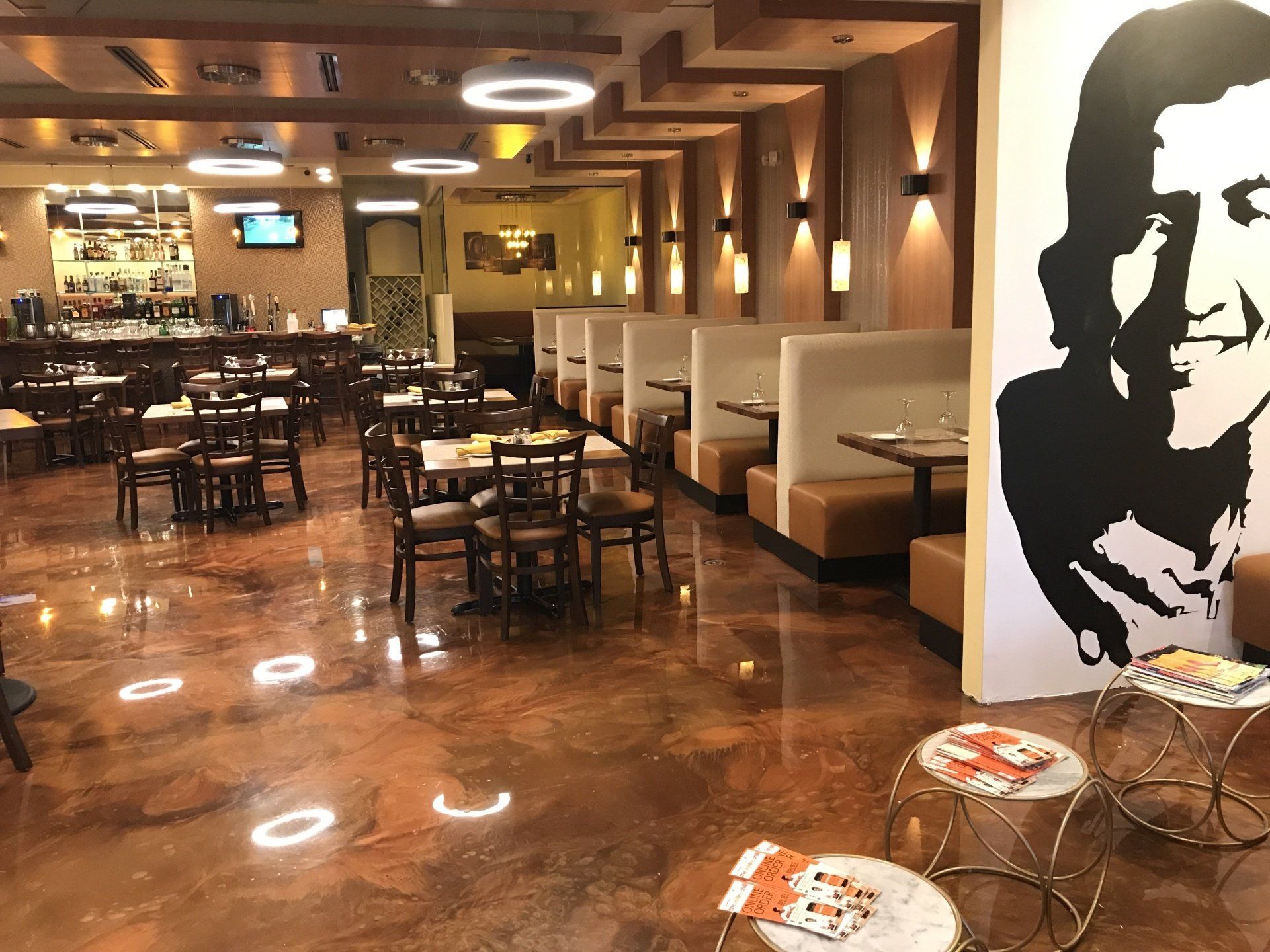 A restaurant with tables and chairs and a painting of che guevara on the wall.