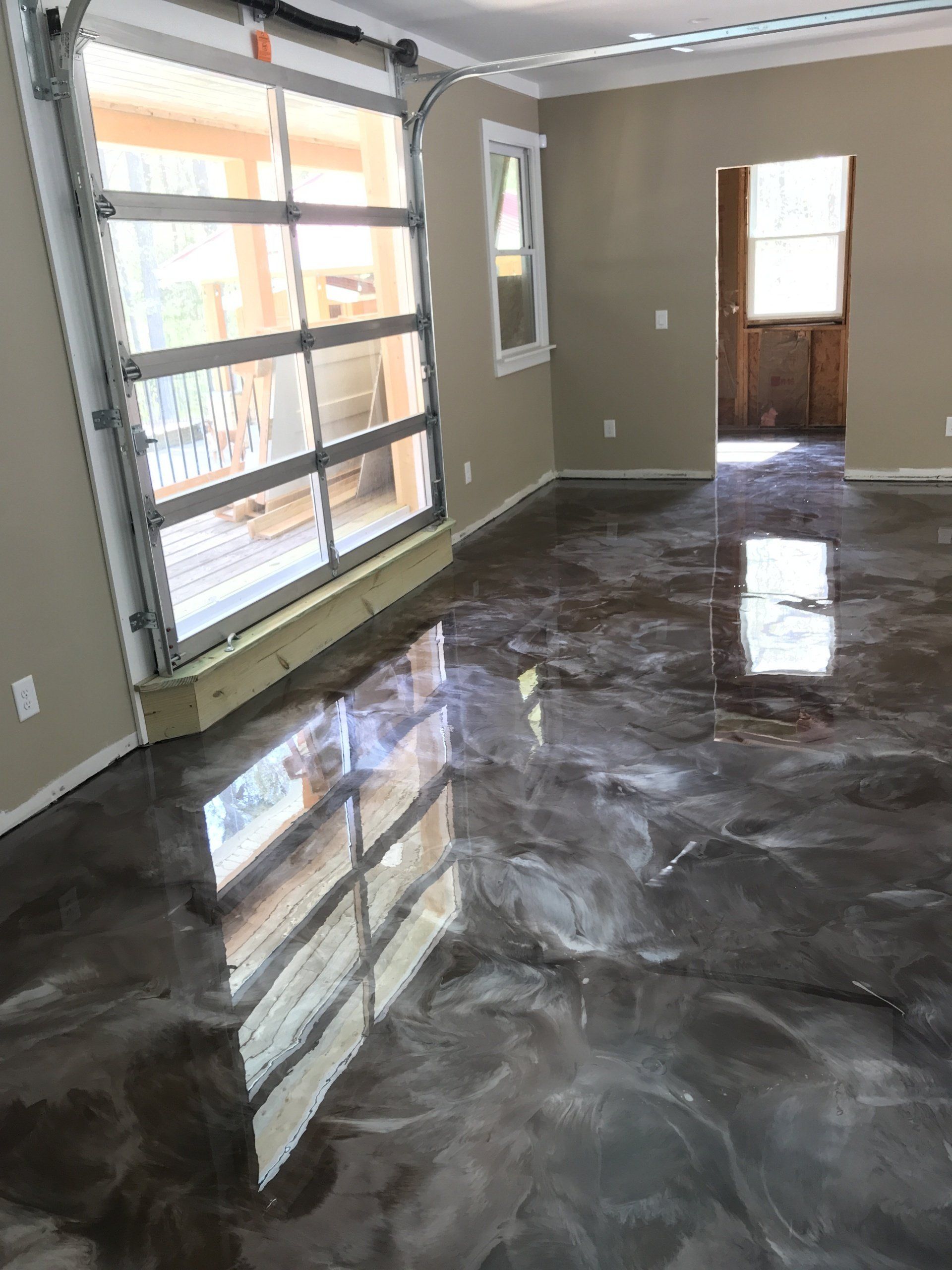 A living room with a metallic floor and a garage door.