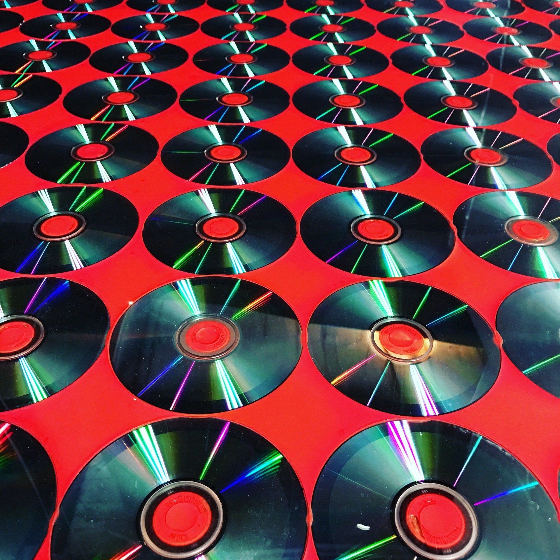 A bunch of cds are lined up on a red surface