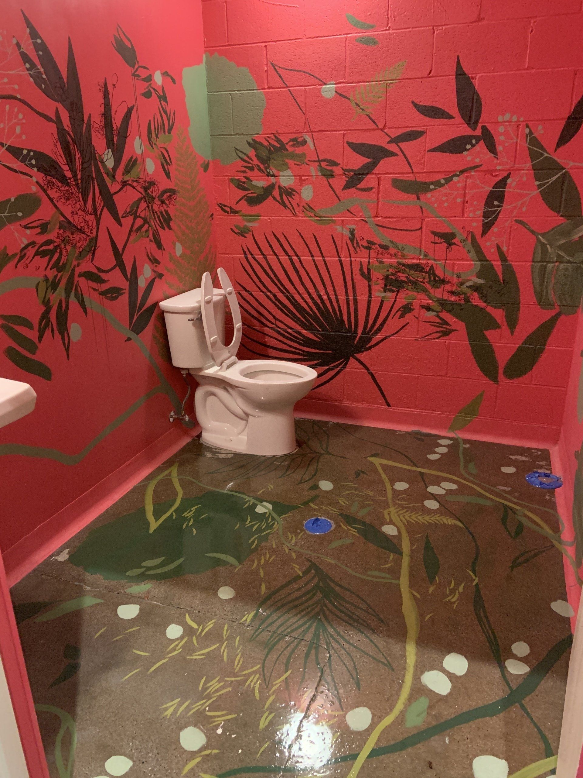 A bathroom with a toilet and a painting on the wall