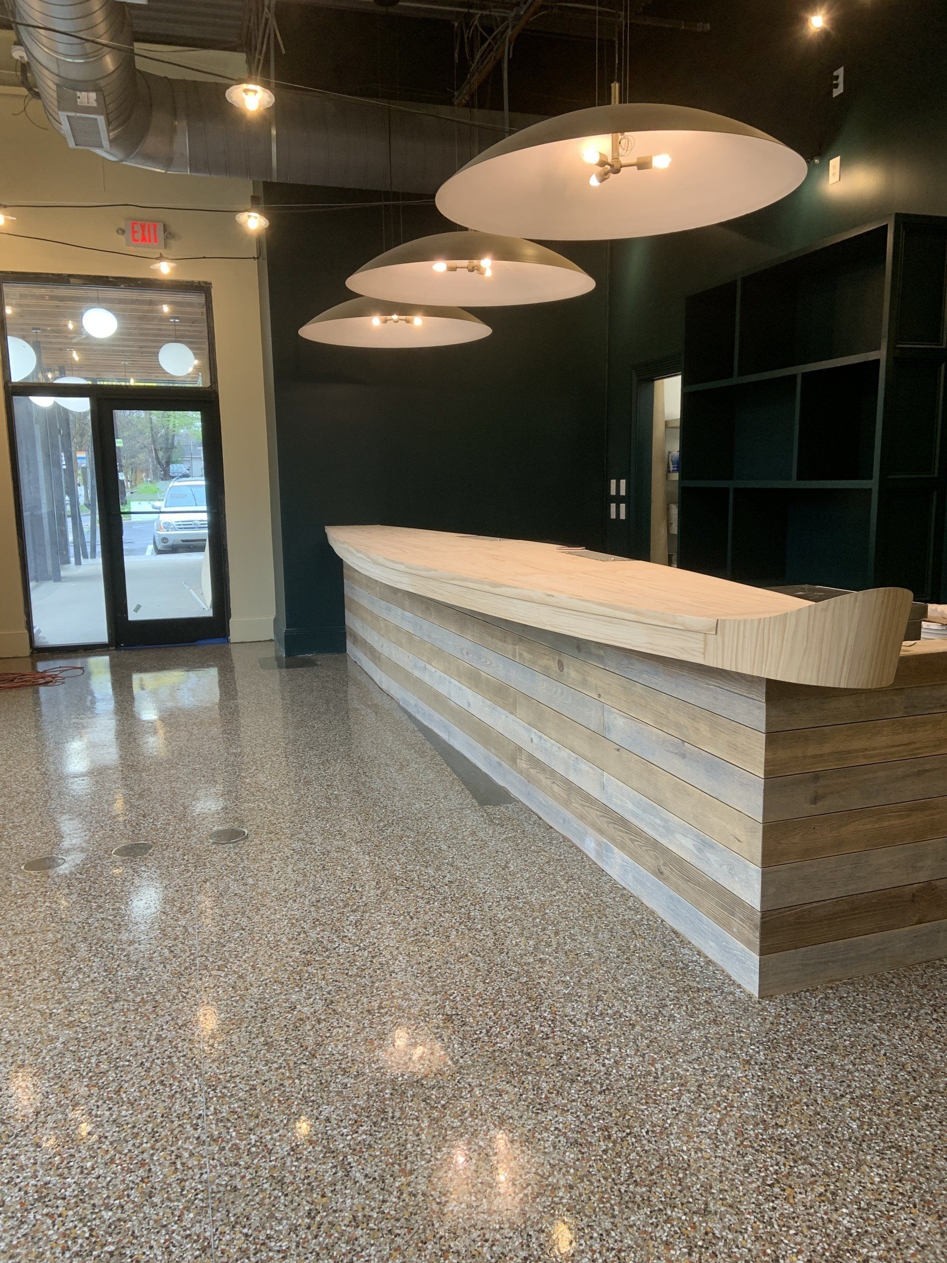 A long wooden counter in an empty room with a marble floor.