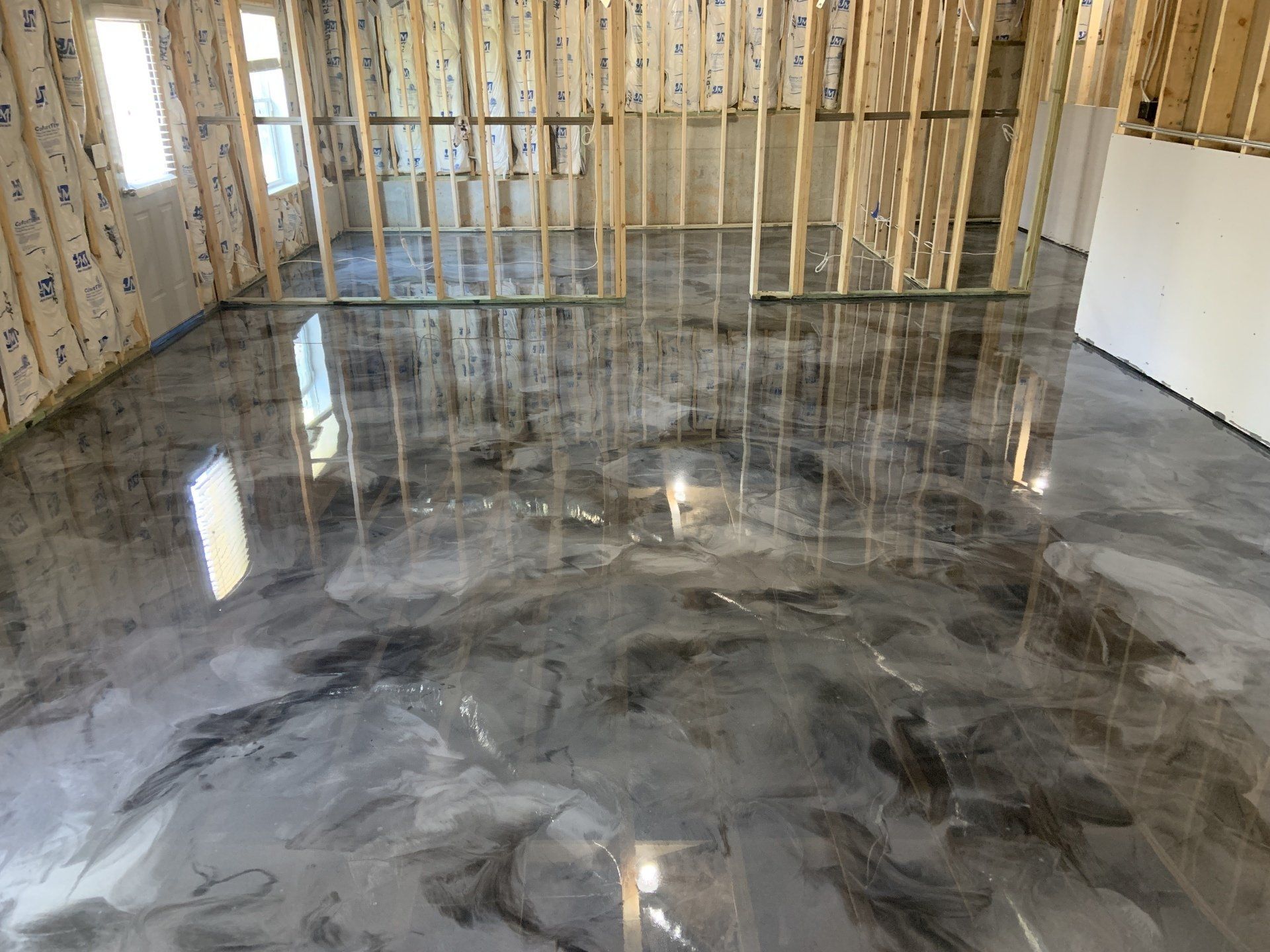 A room with a shiny metallic floor in a house under construction.