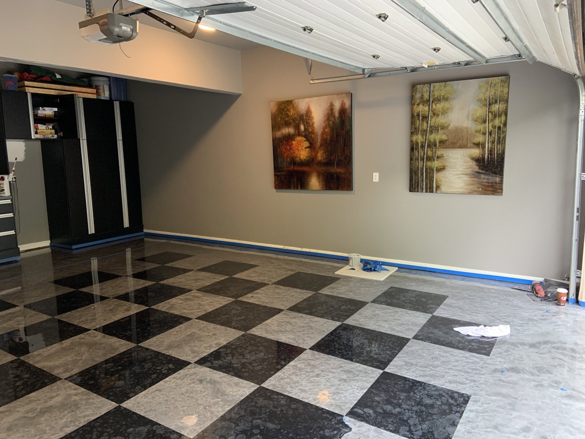 A garage with a checkered floor and two paintings on the wall.