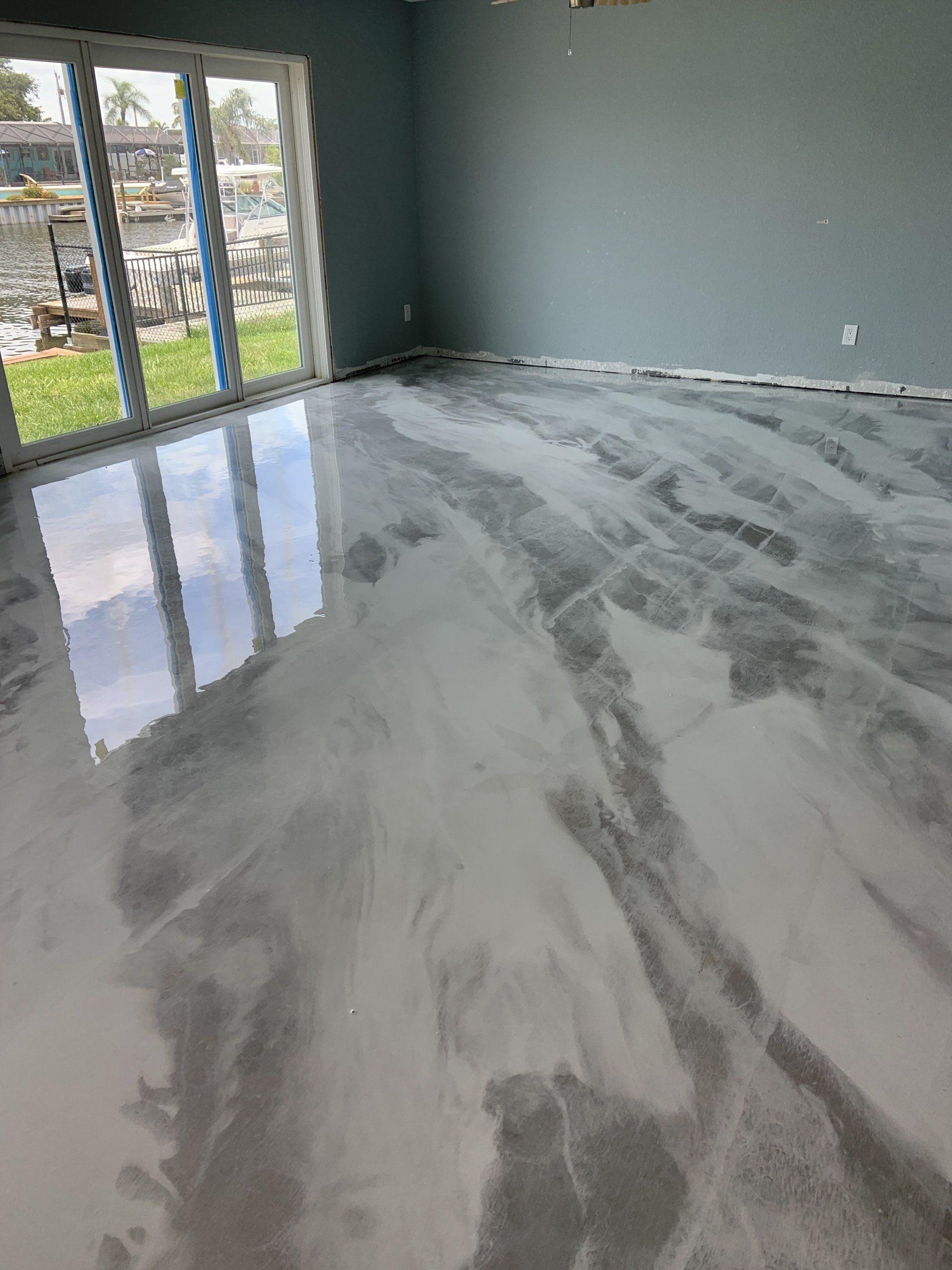 A living room with a shiny metallic floor and a large window.
