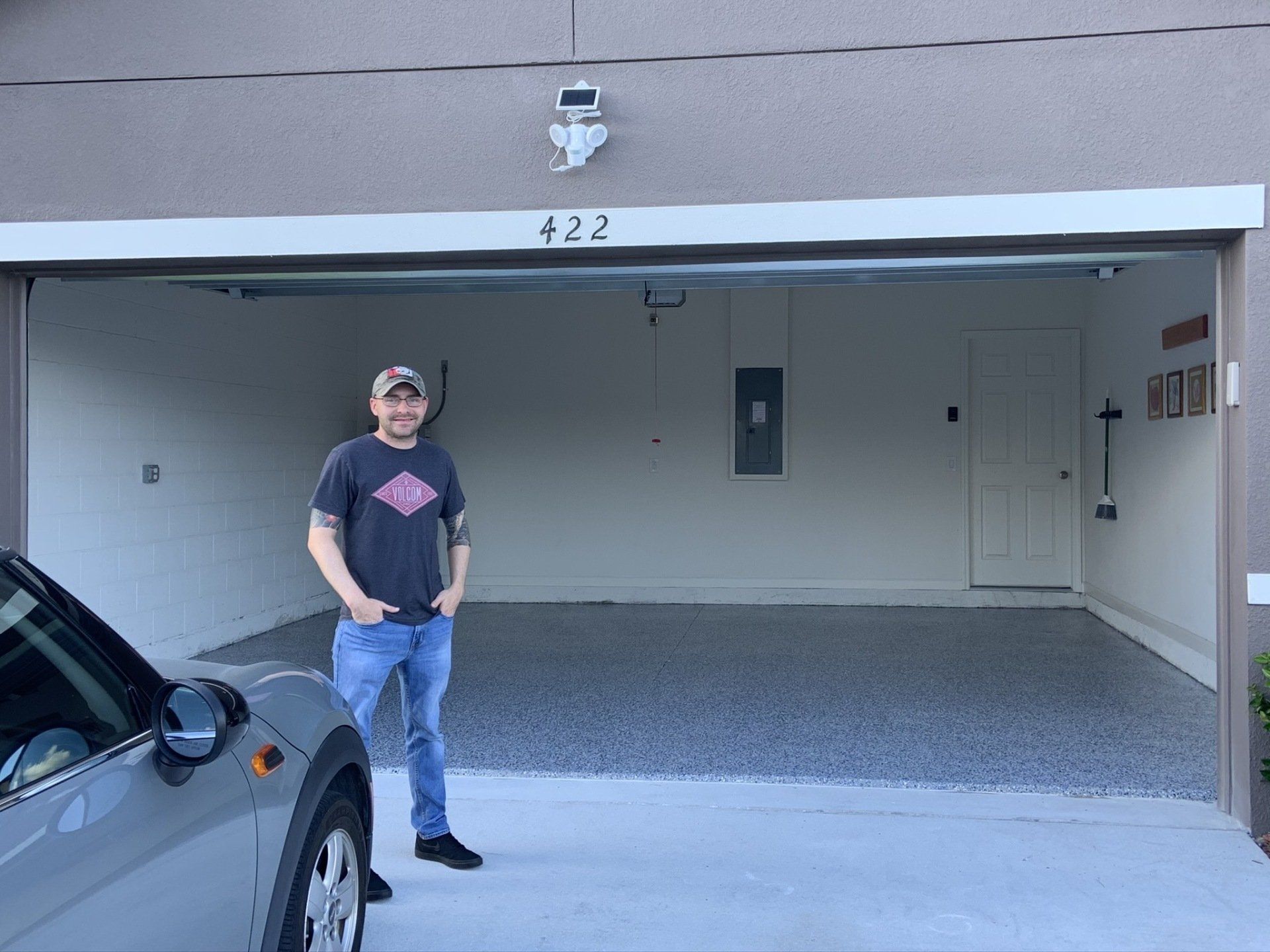 A man is standing in a garage next to a car.