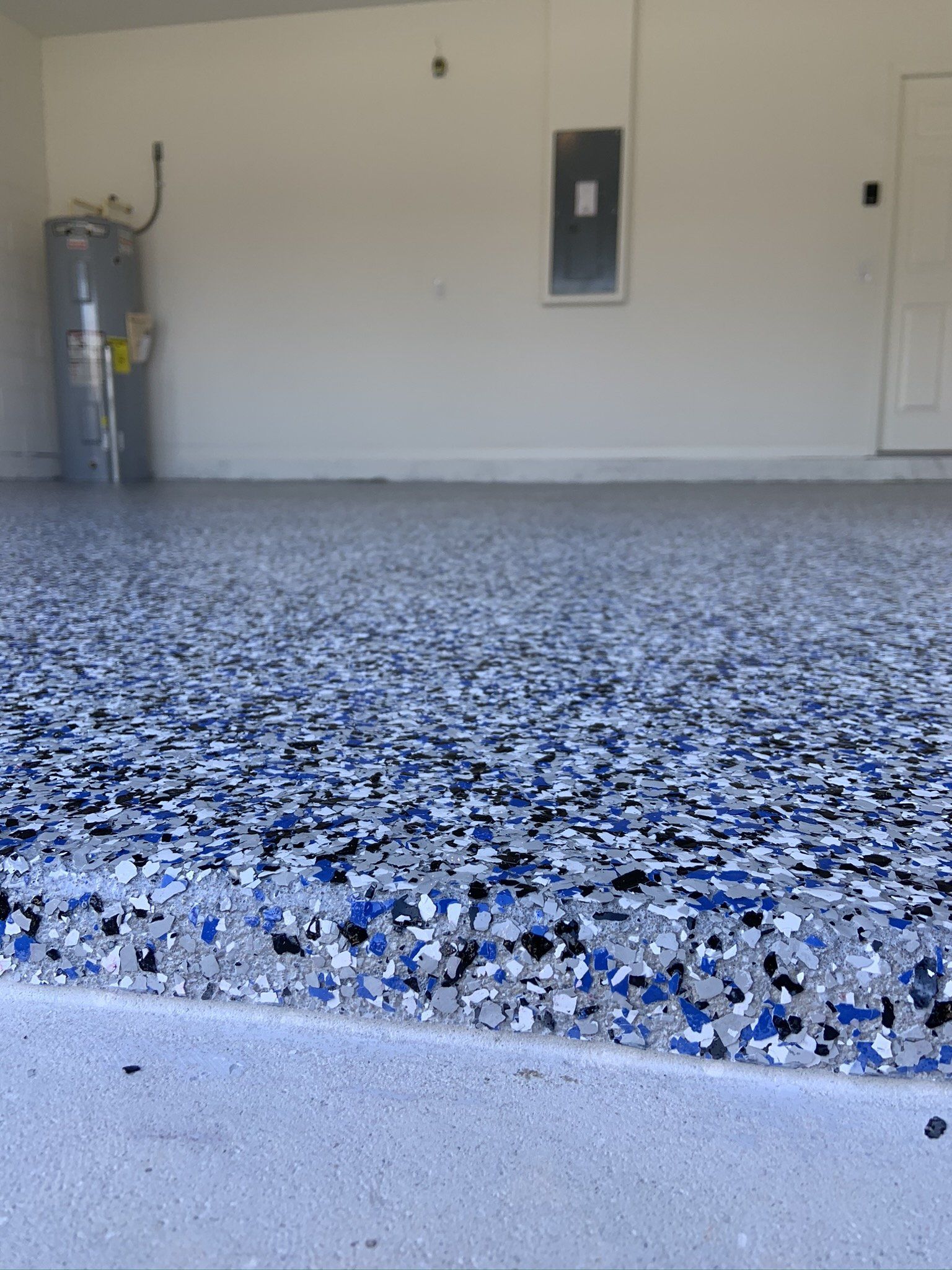 A garage floor with a lot of blue and white flakes on it.