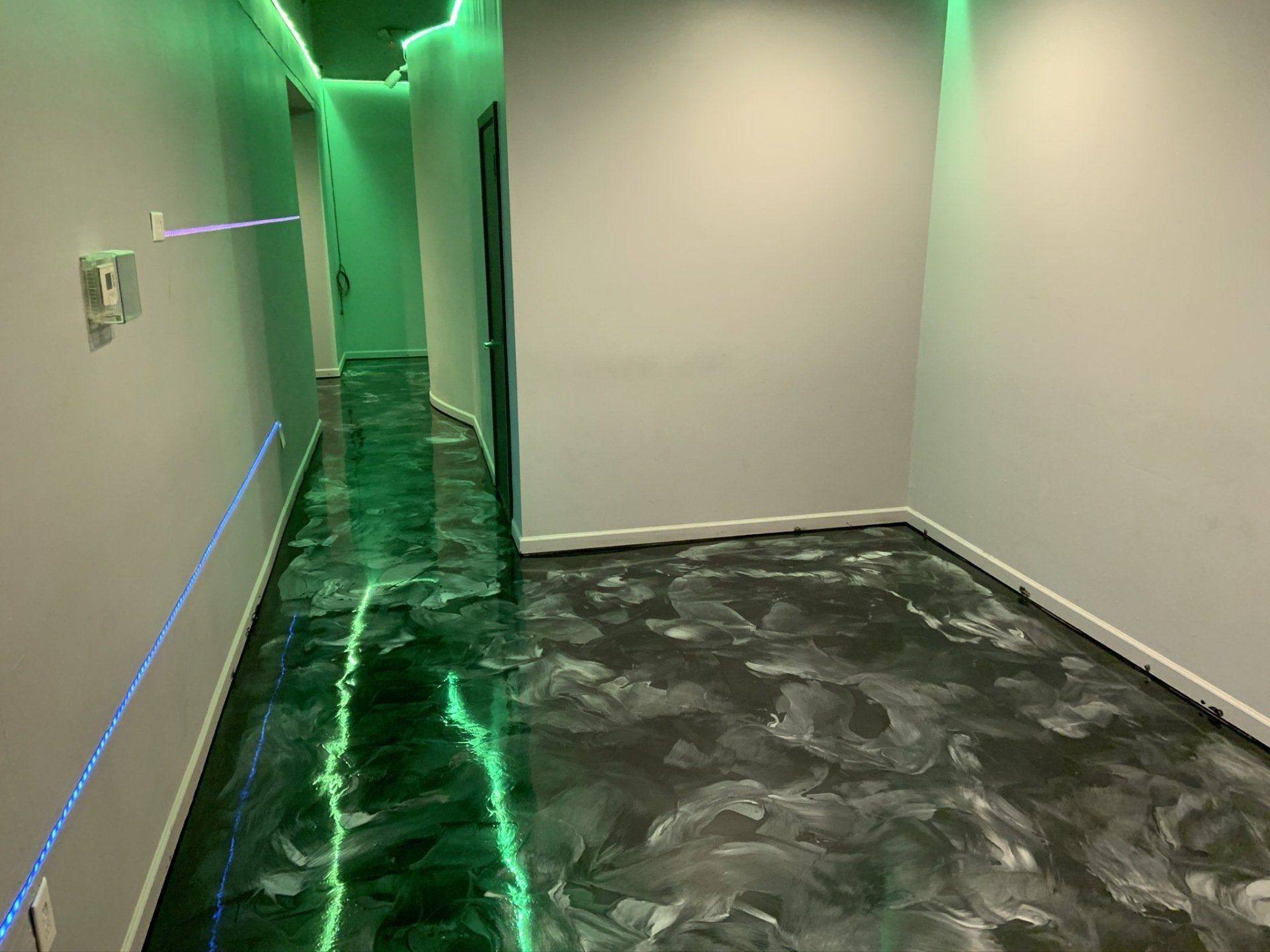 A hallway with a black floor and green lights on the walls.