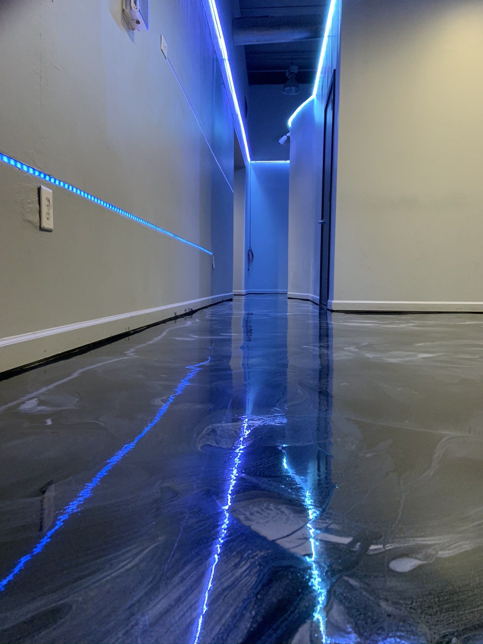 A hallway with a shiny floor and blue lights on the walls.