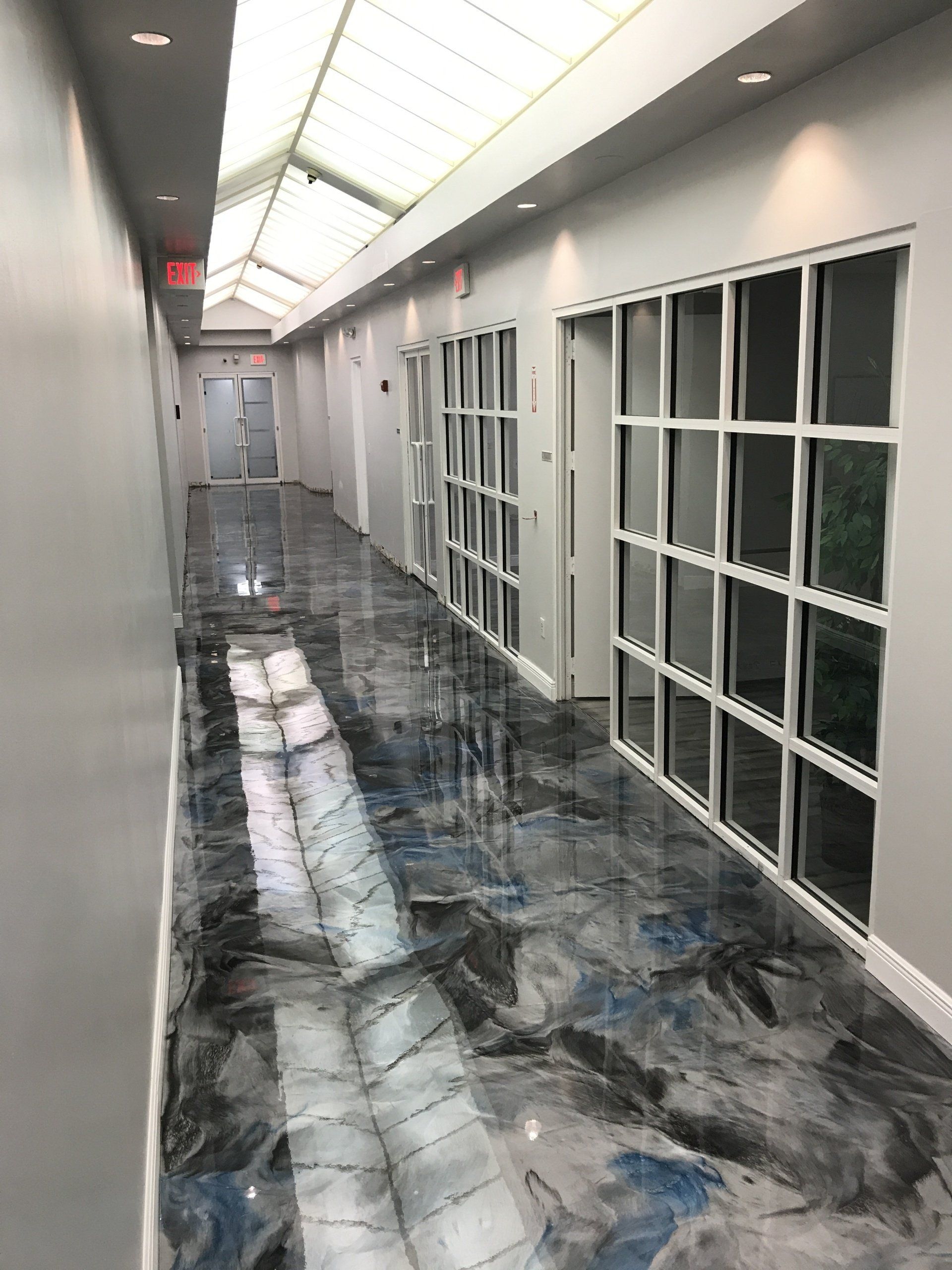 A long hallway with a metallic floor and a lot of windows.