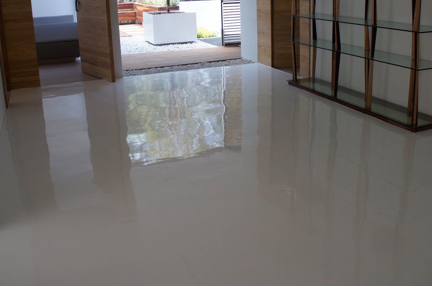 A living room with a shiny white floor and a glass shelf.