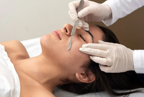 Woman undergoing facial cosmetic surgery; scalpel held near eye. dermaplane