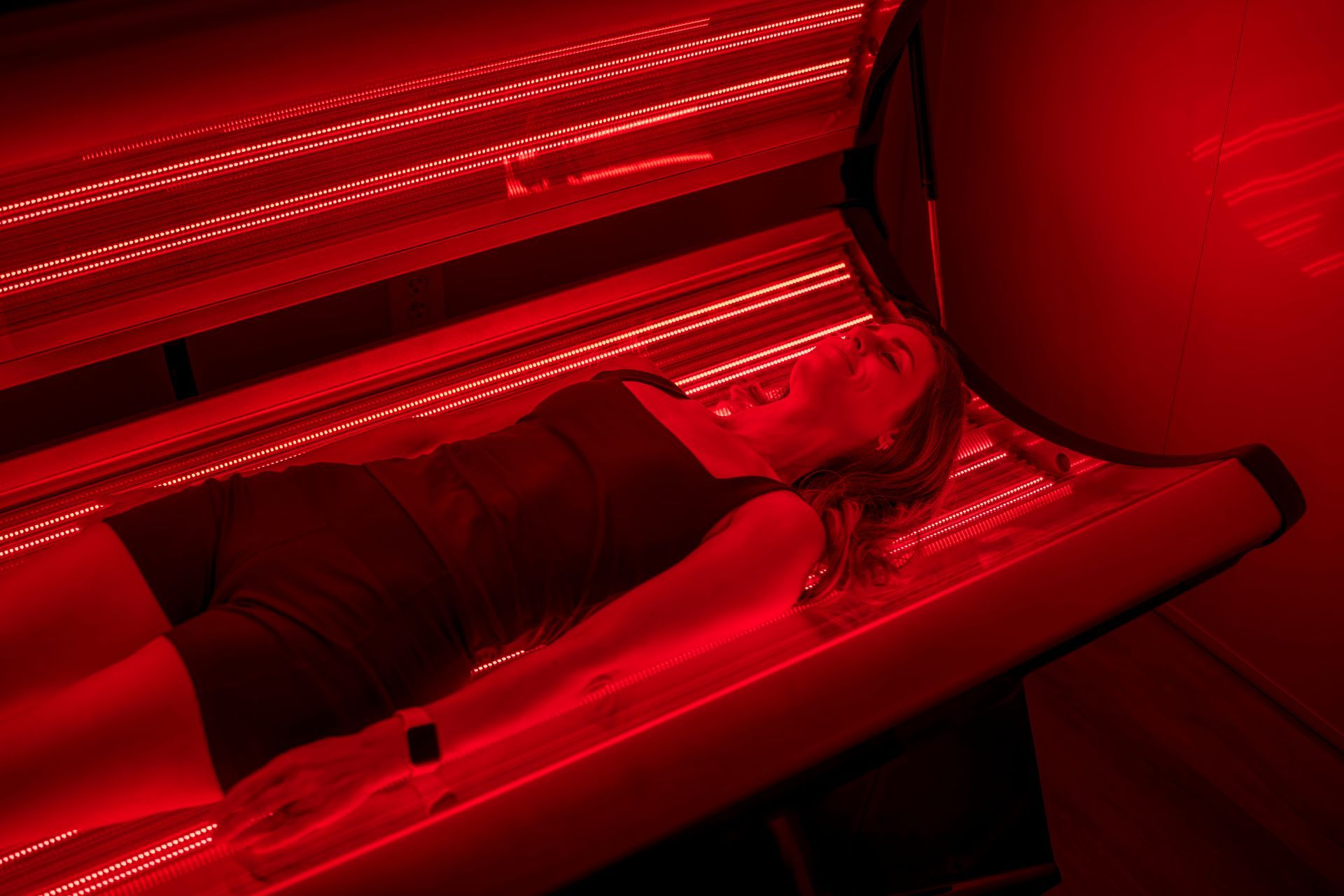 Woman lying in a red light beed. 2 red light requencies and 3 infrared frequencies