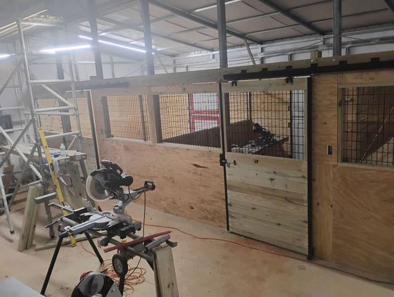 Interior barn under construction with wood walls, sliding door, and miter saw.