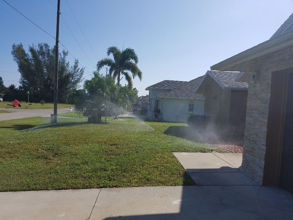A lawn sprinkler is spraying water on a lush green lawn