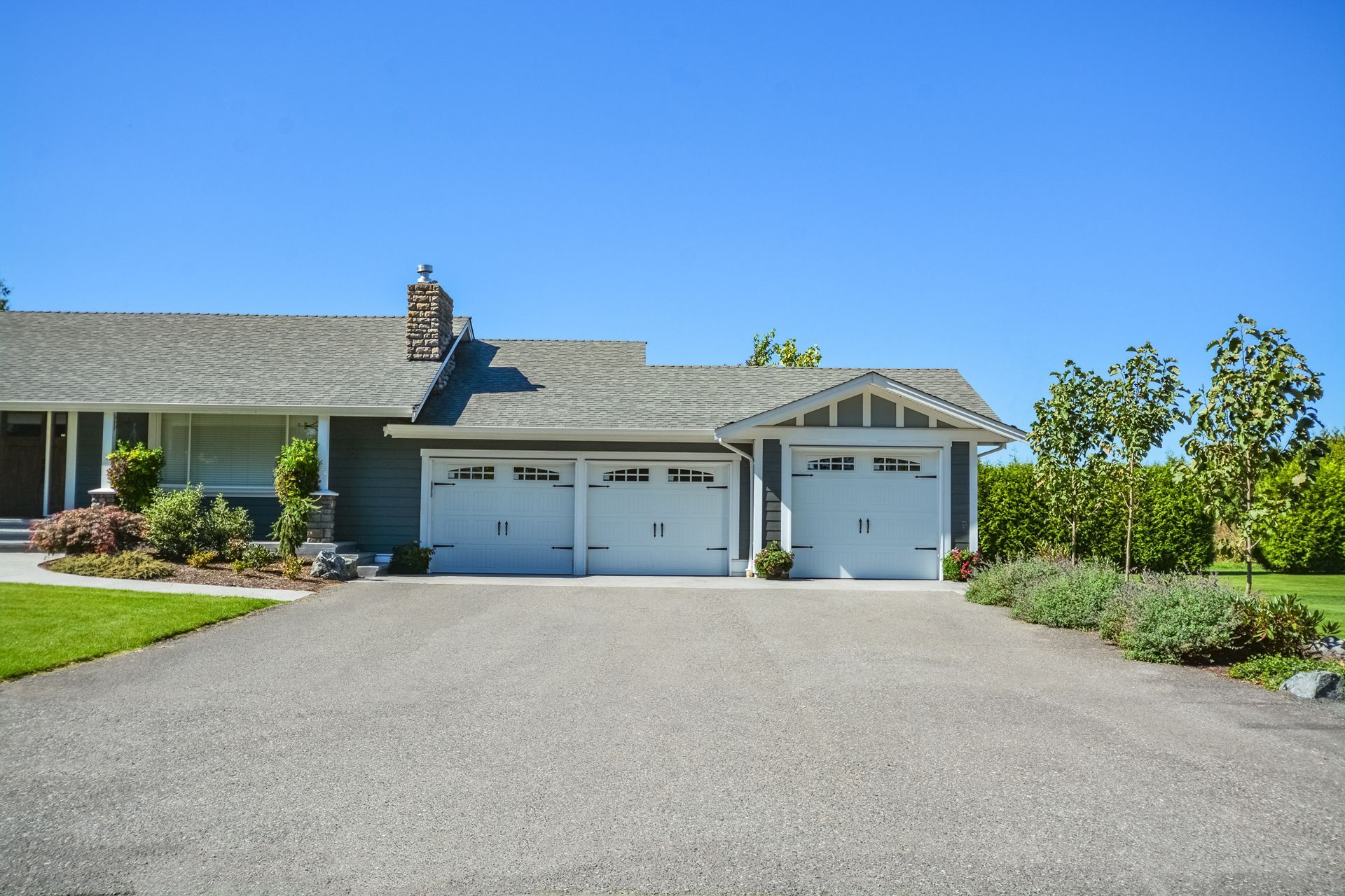 A house with three garage doors and a gravel driveway