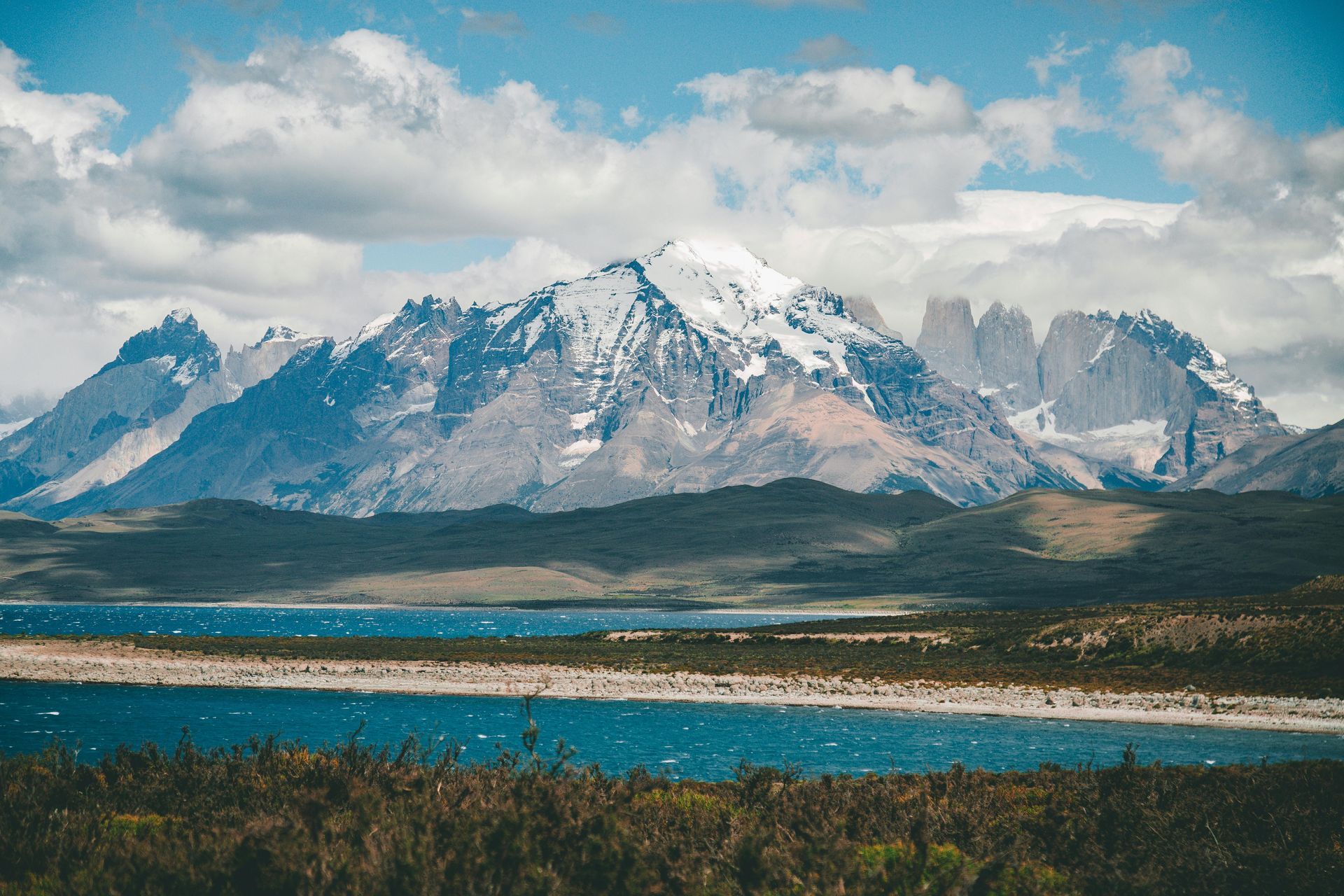 Snow-capped mountains rise above a blue lake in Torres del Paine National Park, Patagonia.