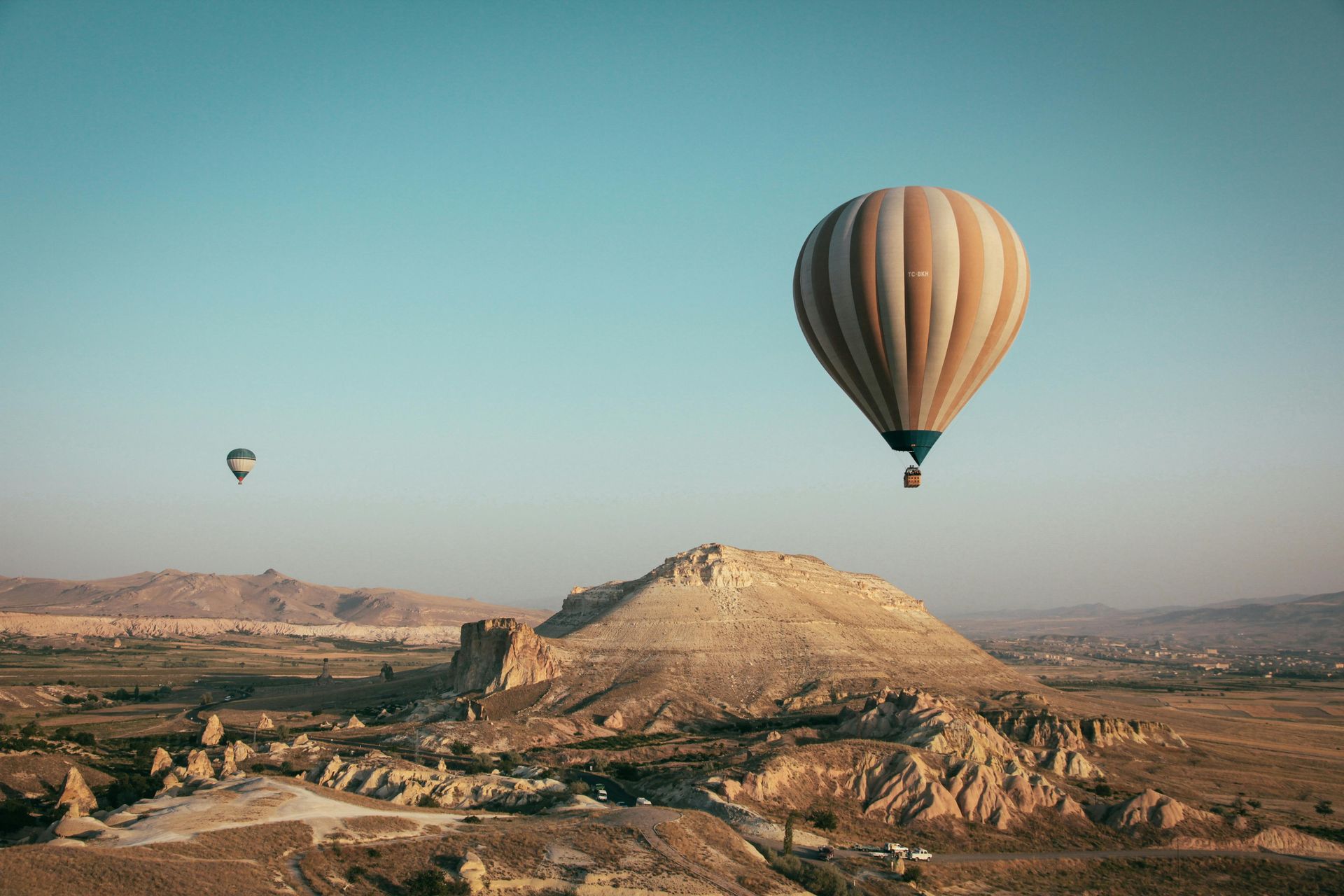 Two hot air balloons floating over a desert landscape.