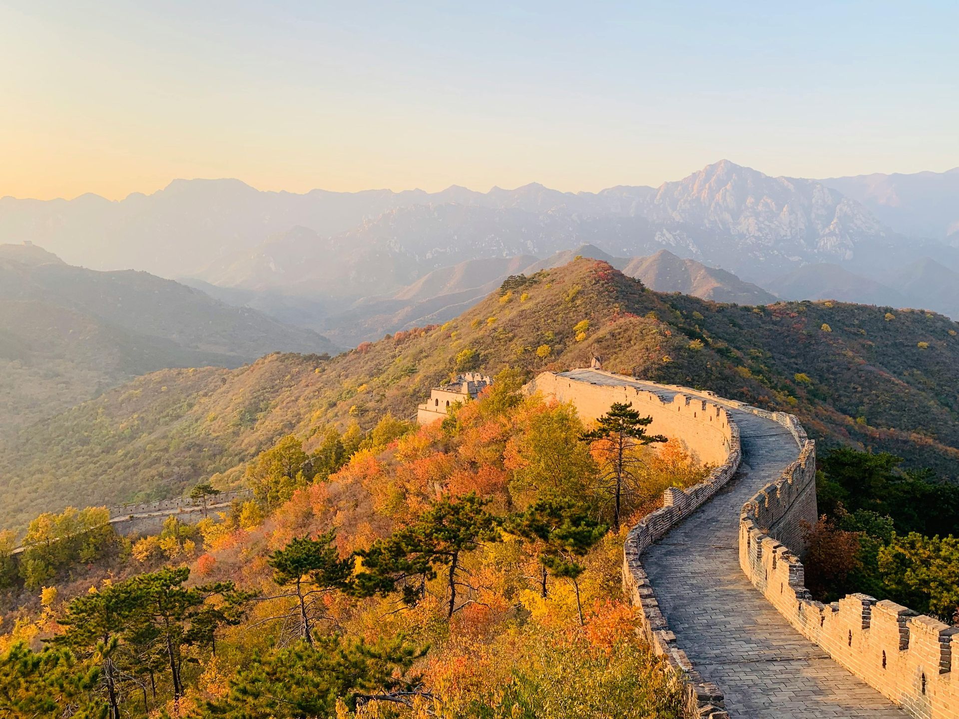 Great Wall of China winds along a mountain ridge, bathed in warm sunlight.
