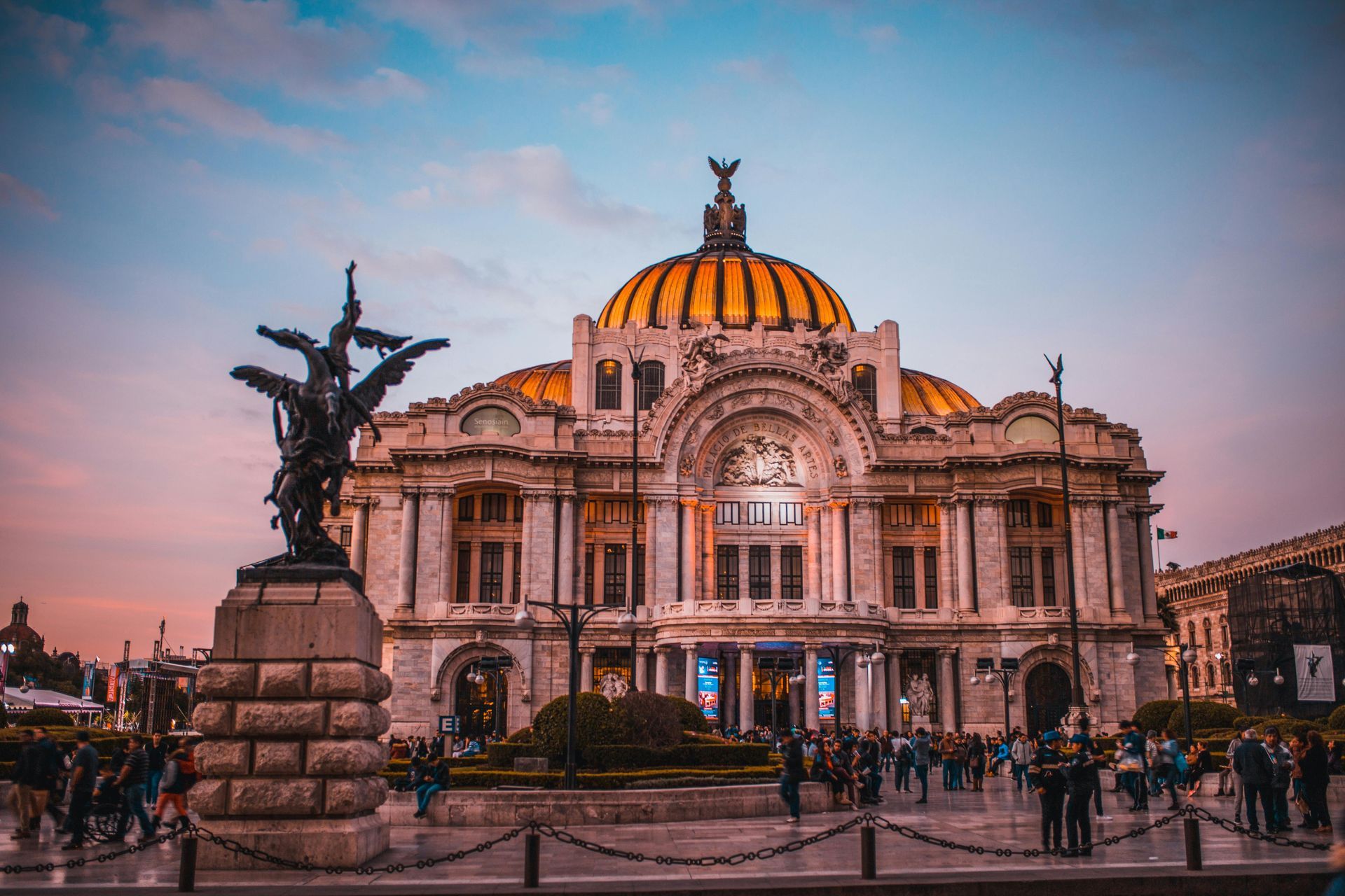Palacio de Bellas Artes, Mexico City, with a bronze statue in front and people milling about.