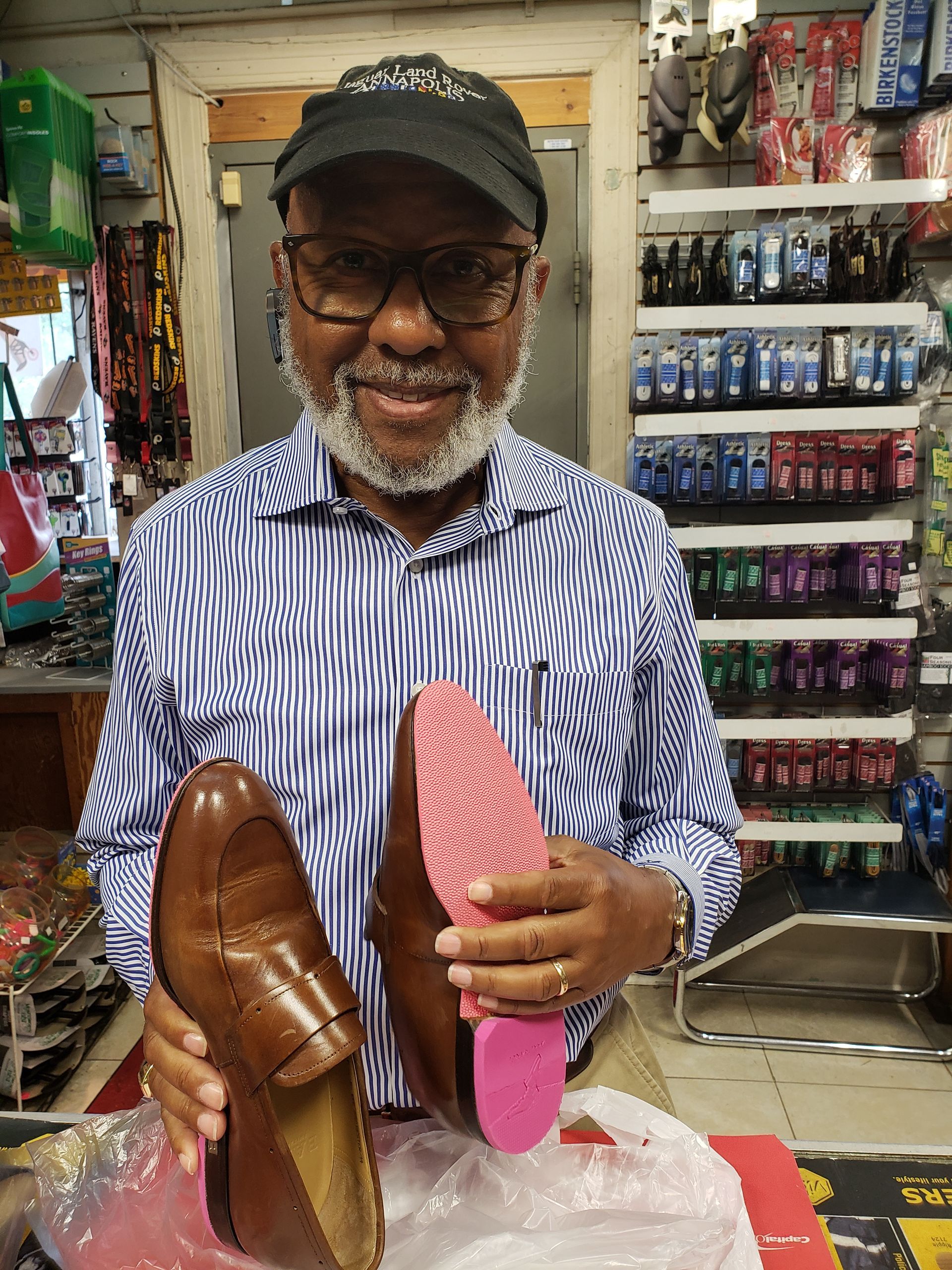 Man holding two brown leather shoes with a pink insole in a store.
