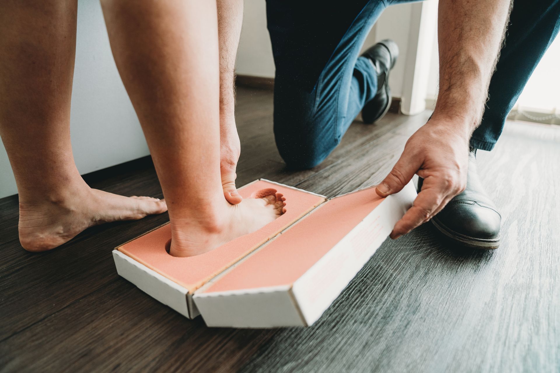 A professional is taking the footprints of a young woman to build new shoe insoles.