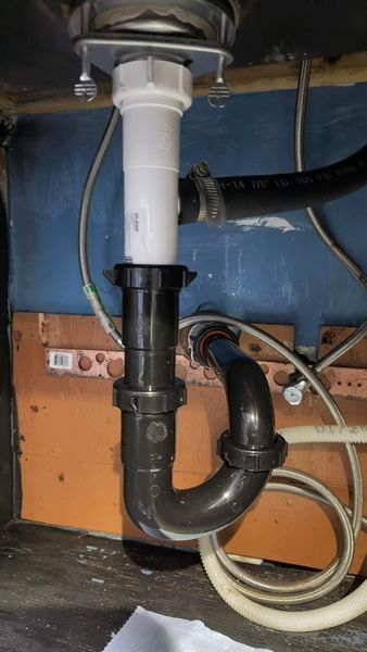 Under-sink plumbing: white and black pipes connected, forming a P-trap