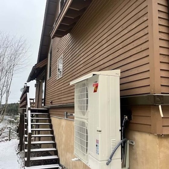 A brown house with a white air conditioner on the side of it.
