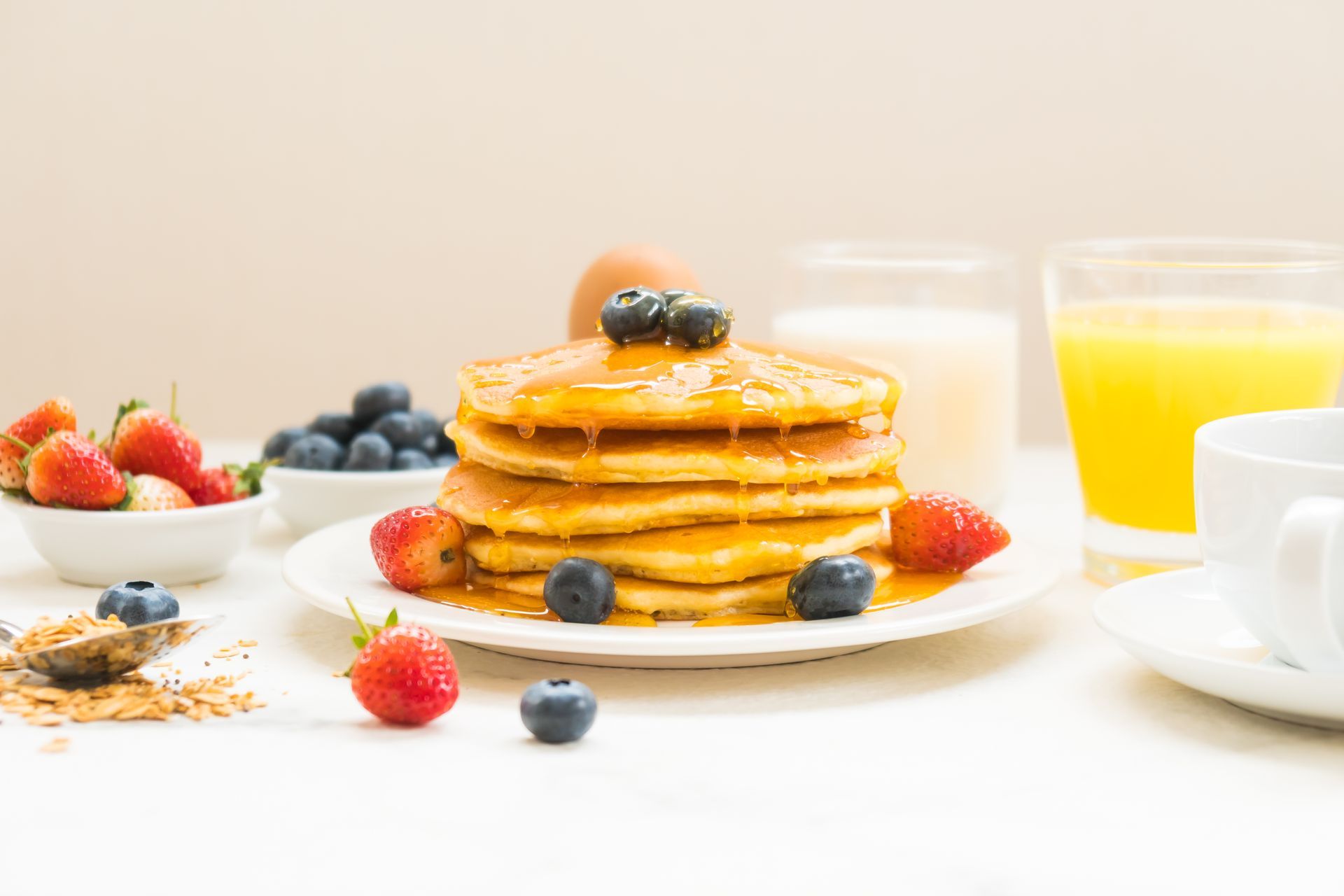 A stack of pancakes with syrup and berries on a plate.