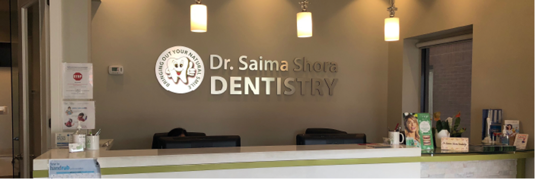 A dentist 's office with a reception desk and a sign on the wall.