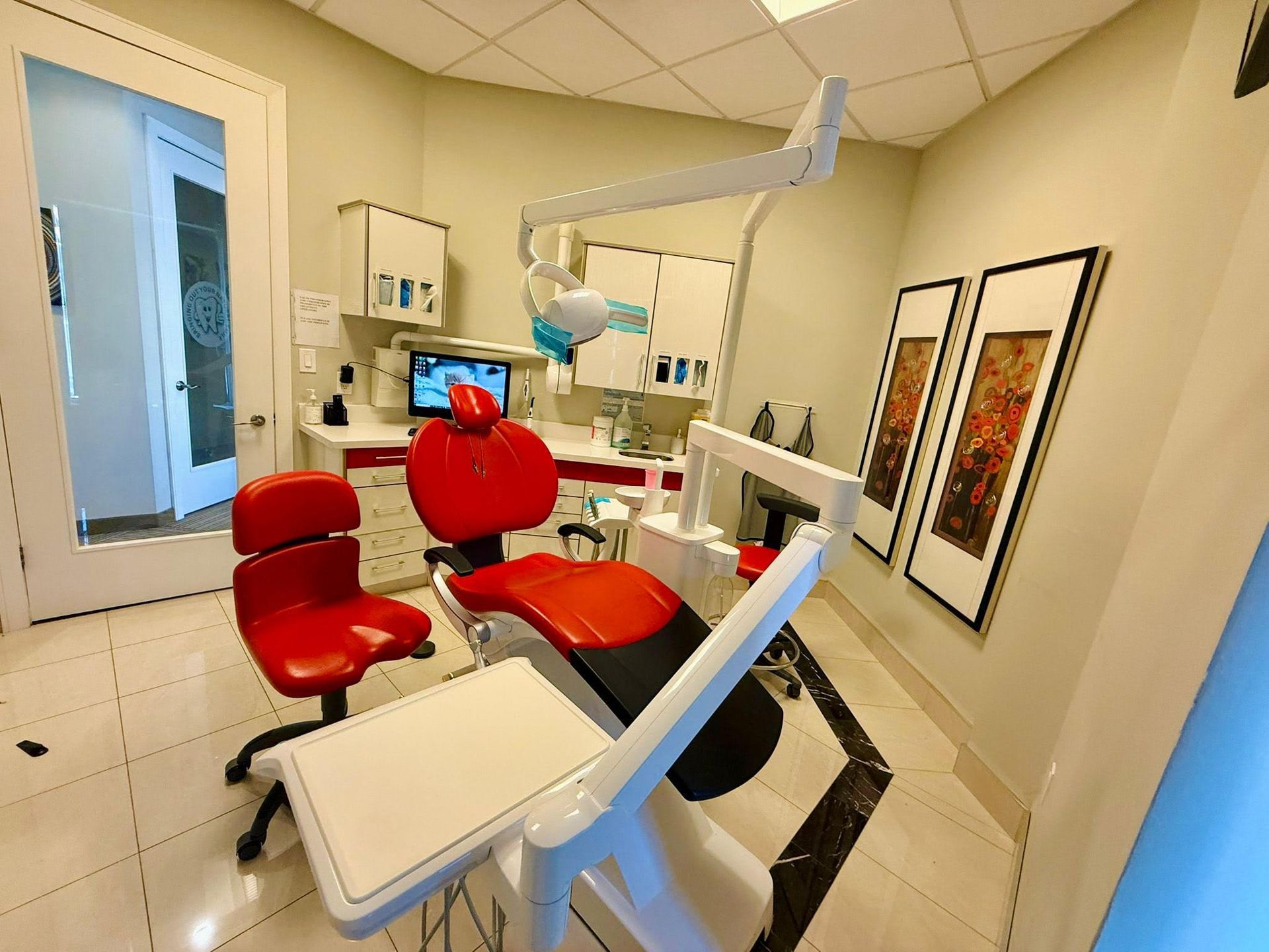 A dental office with a red chair and a computer.