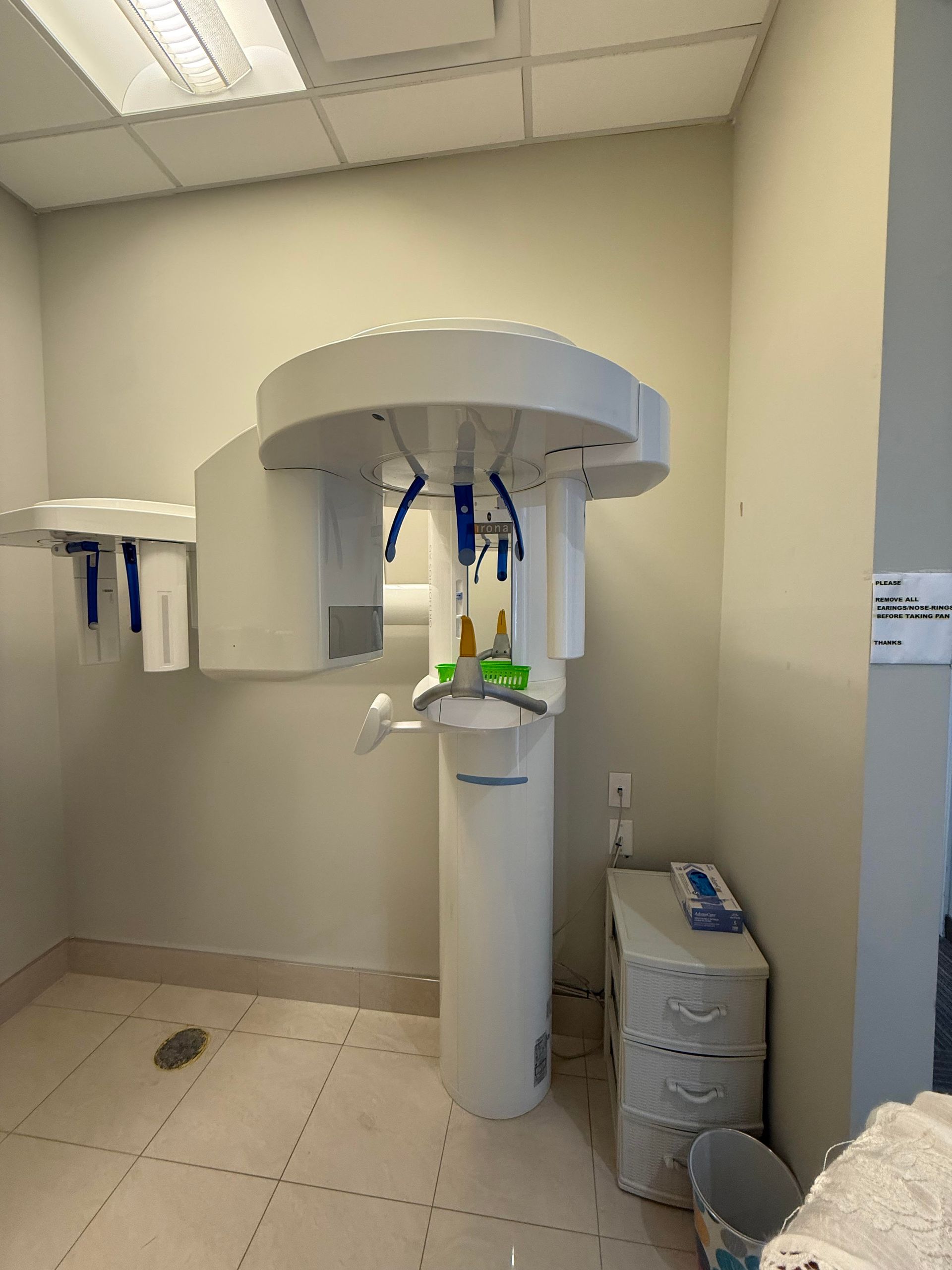 A dental office with a x-ray machine in the middle of the room.